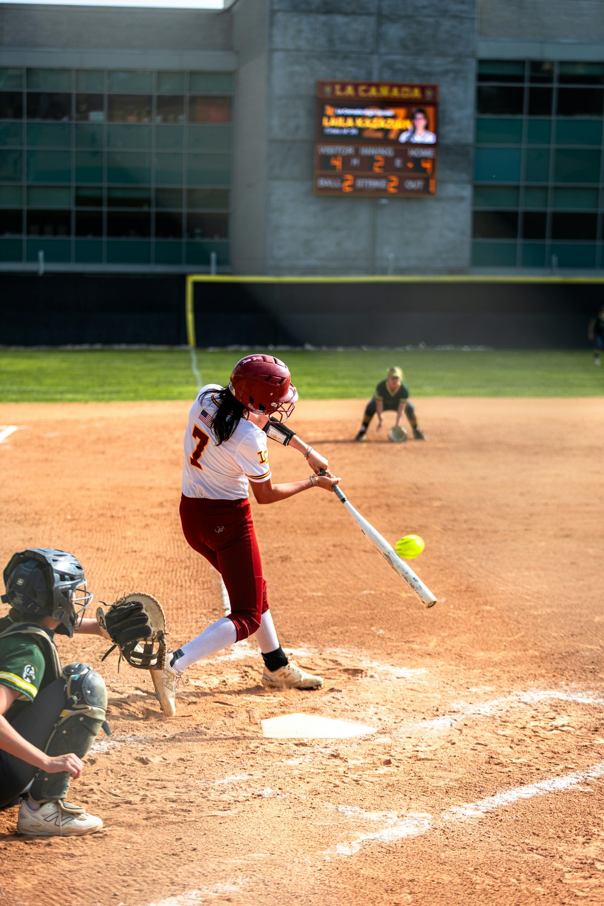 Female high school softball player swinging at a pitch