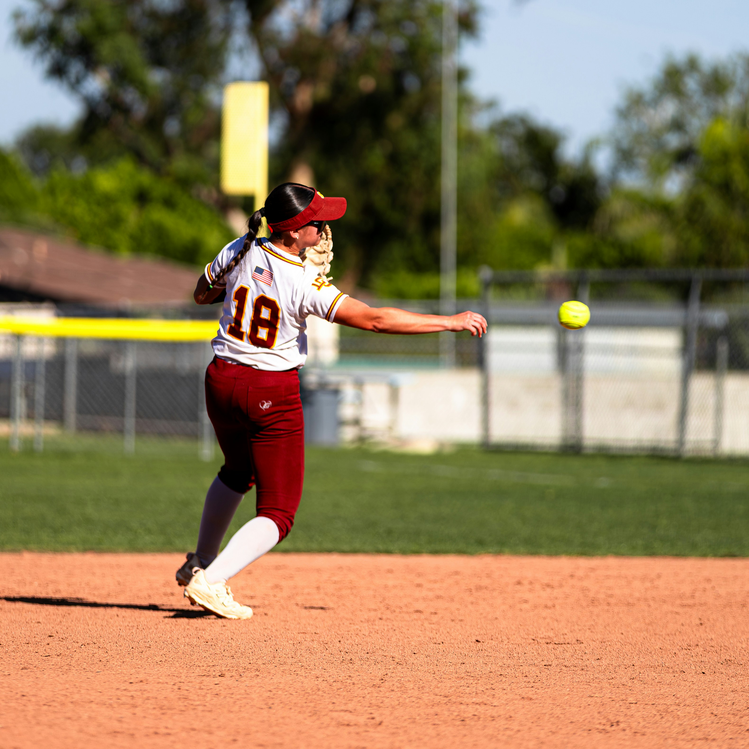 A softball player throws the ball during a game.