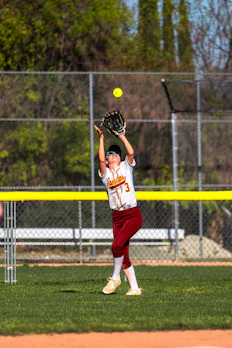 A softball player catches a ball in the air