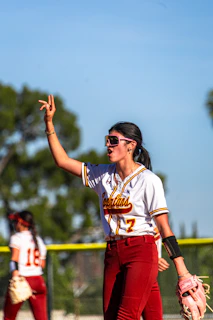 Softball player in uniform signals on the field.