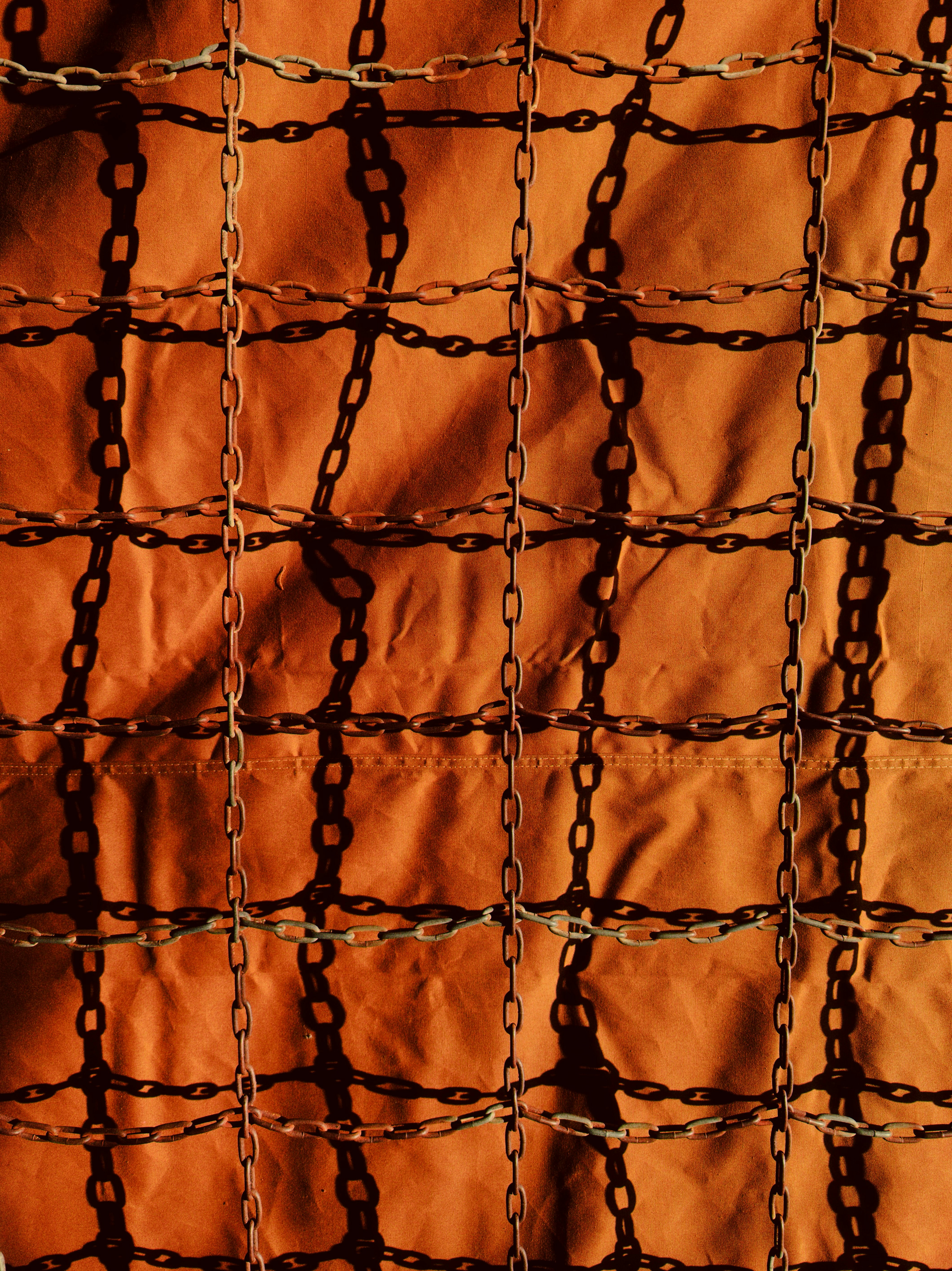 Chains casting shadows on an orange textured surface - 相关推荐
