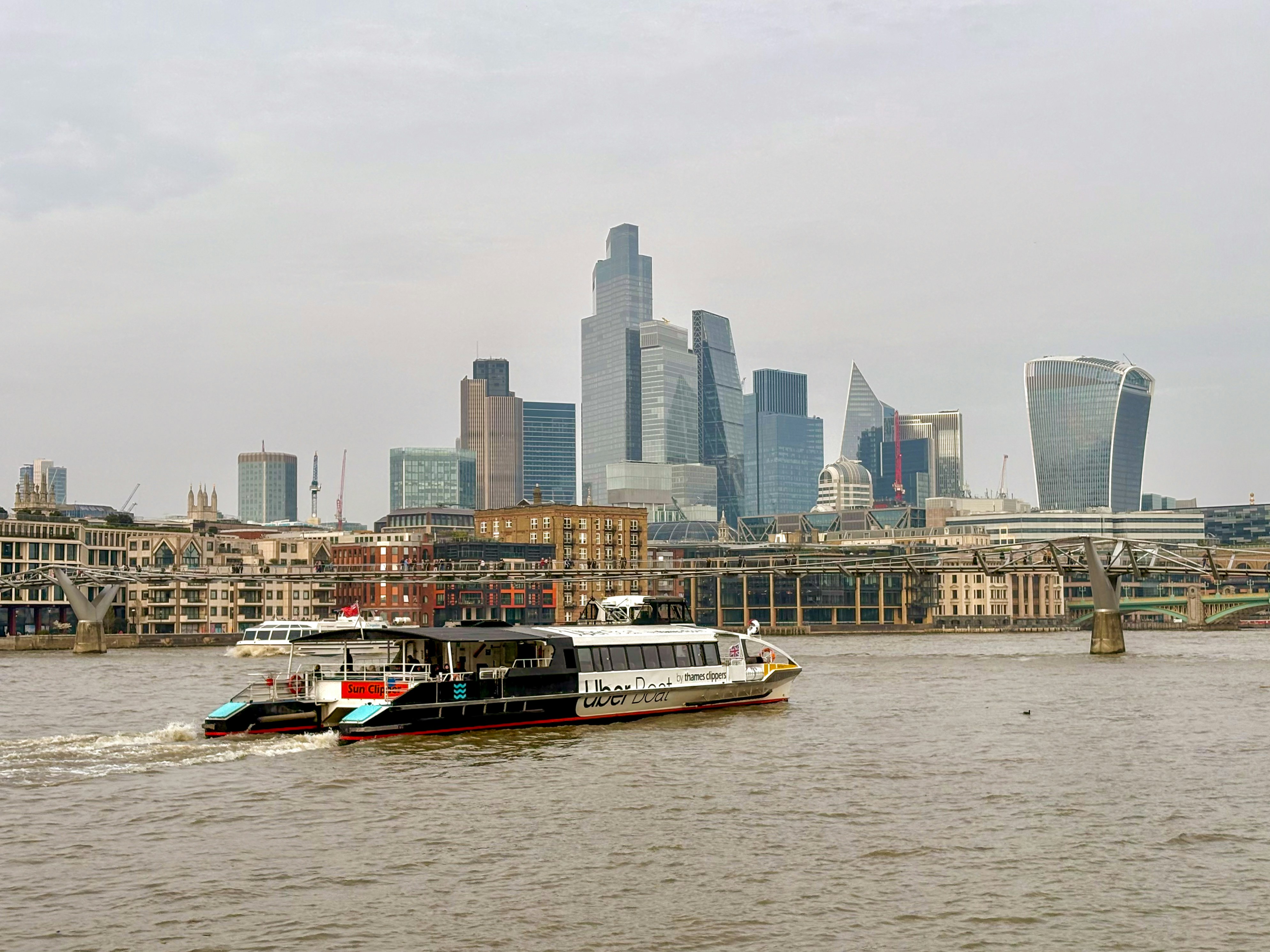 Eine moderne Fähre fährt auf der Themse mit Londoner Skyline.