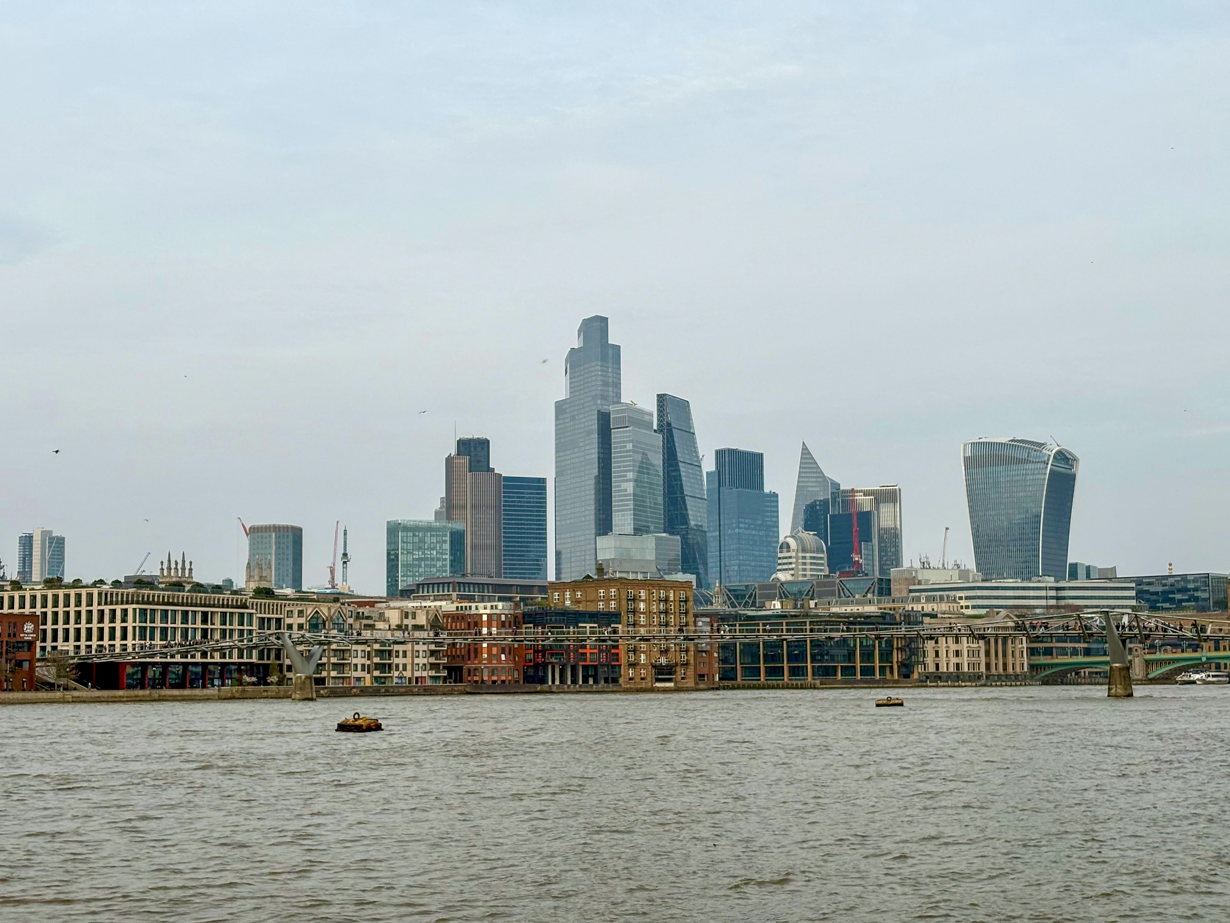 Moderne Wolkenkratzer ragen über historischen Gebäuden am Fluss empor.