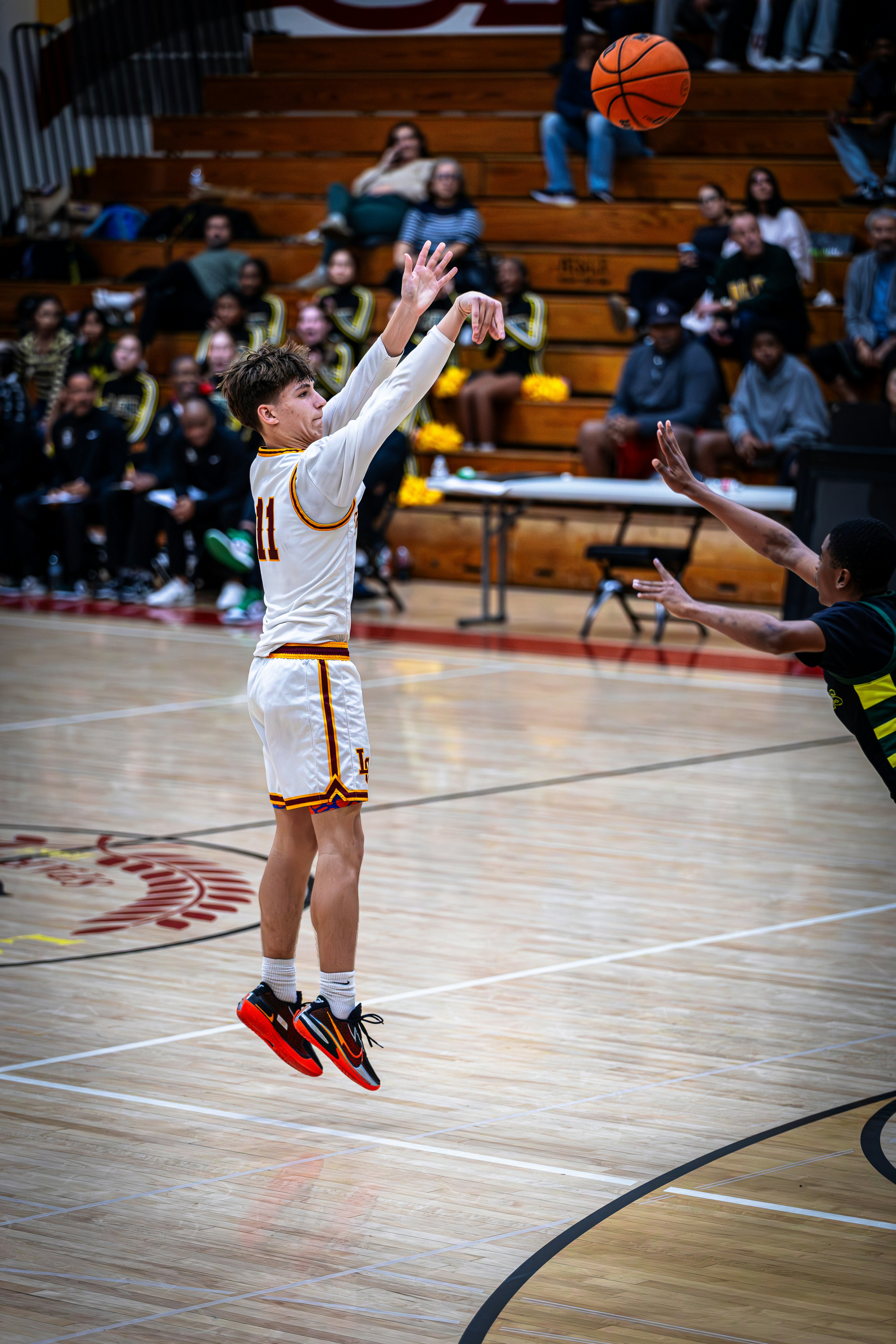 Teenage basketball player shooting a jump shot during a game.