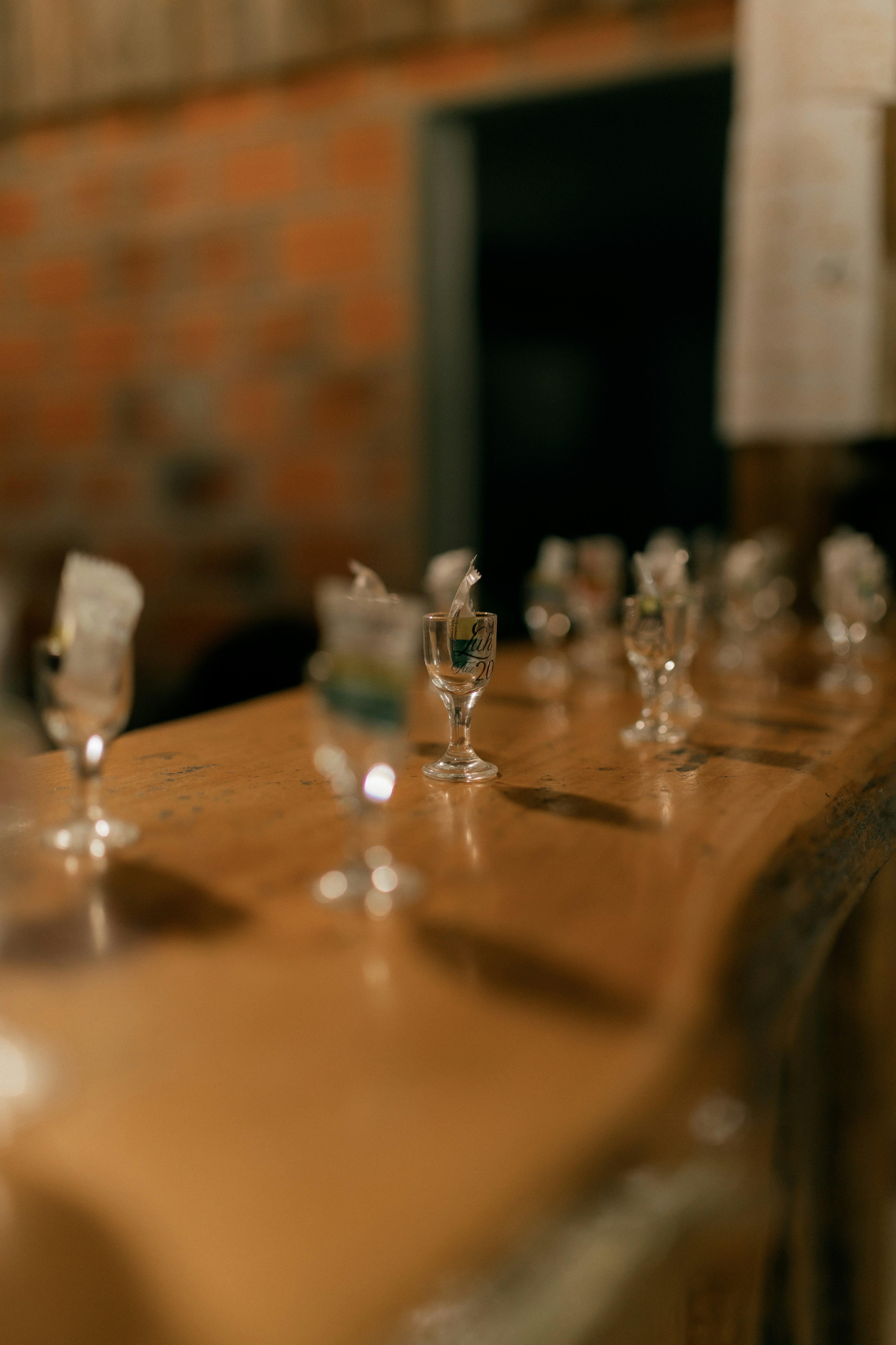 Small glasses lined up on a wooden bar counter