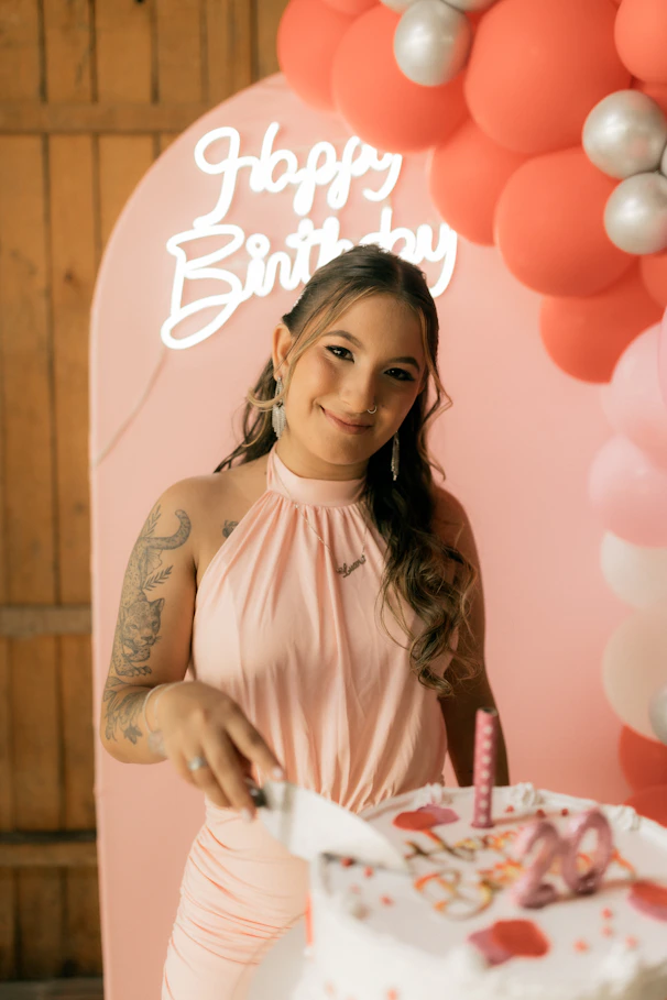 Young woman cutting a birthday cake with candles.
