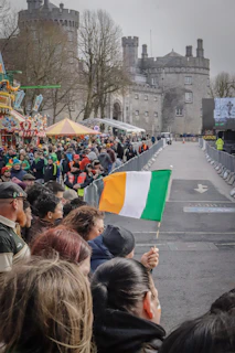 Crowd watches parade with irish flag near castle