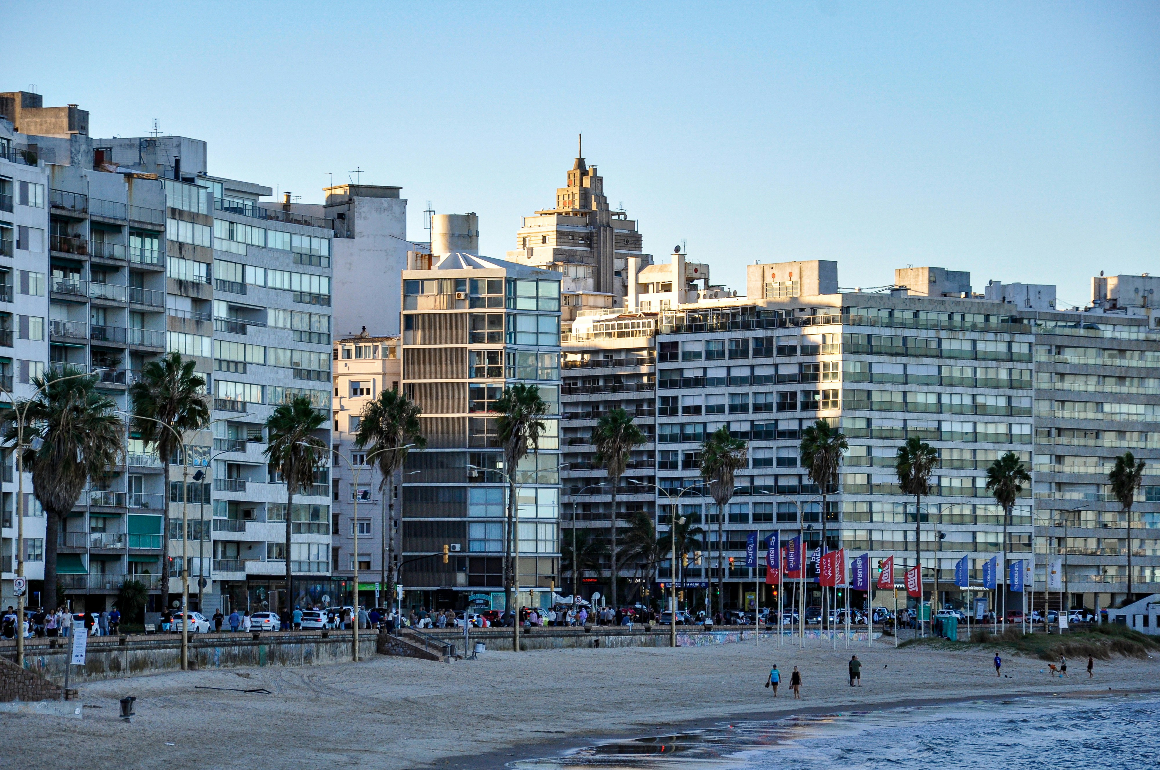 Beachfront buildings with palm trees and ocean waves.
