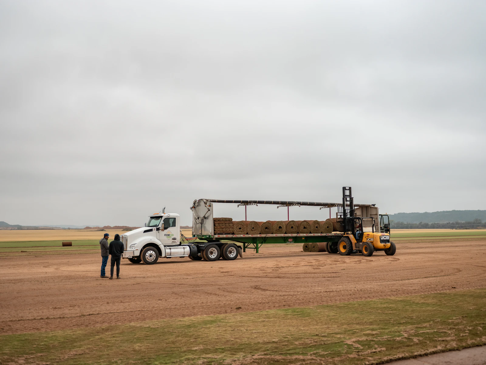 Forklift loading hay bales onto a semi-trailer truck