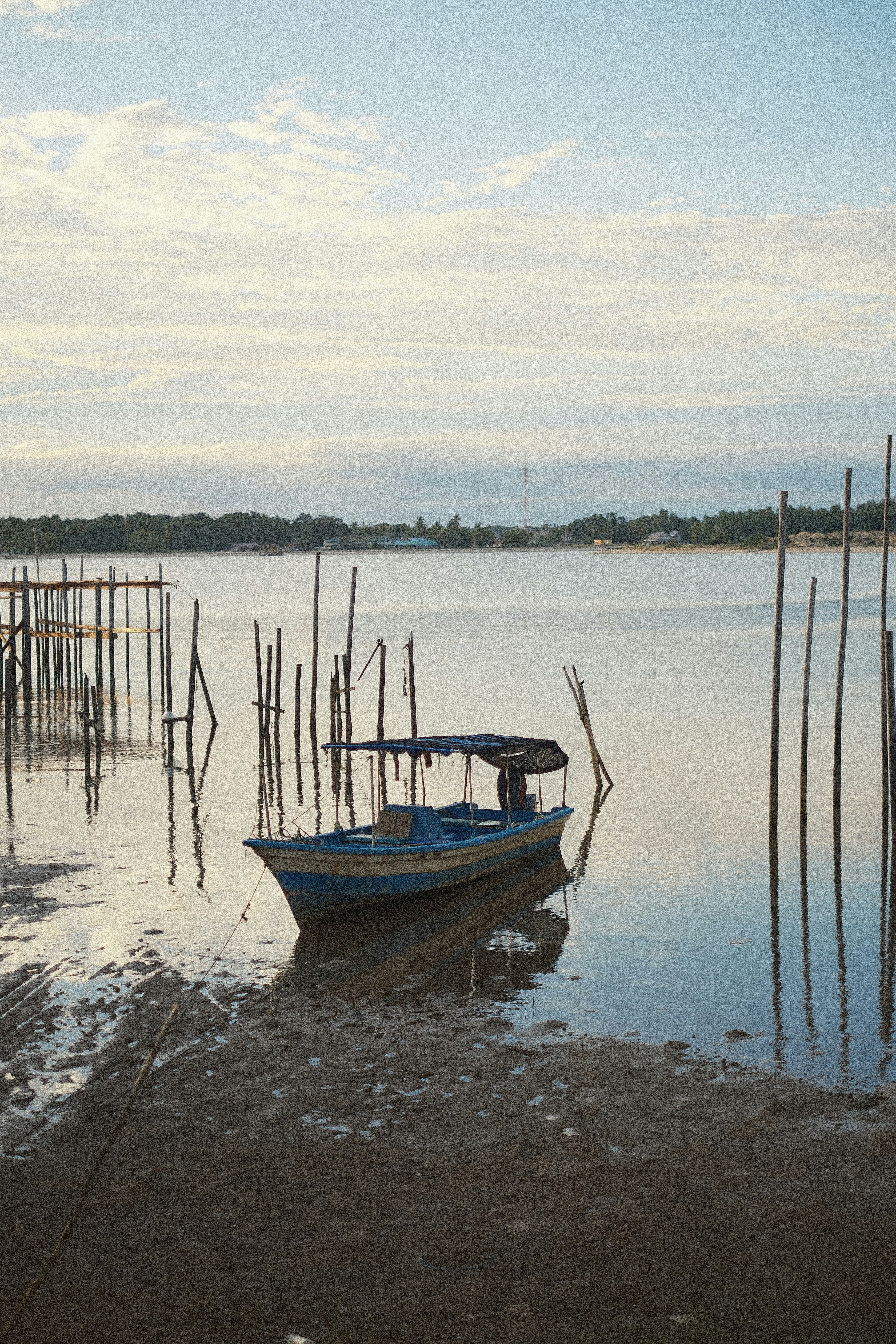 A small blue boat rests on a muddy shore.
