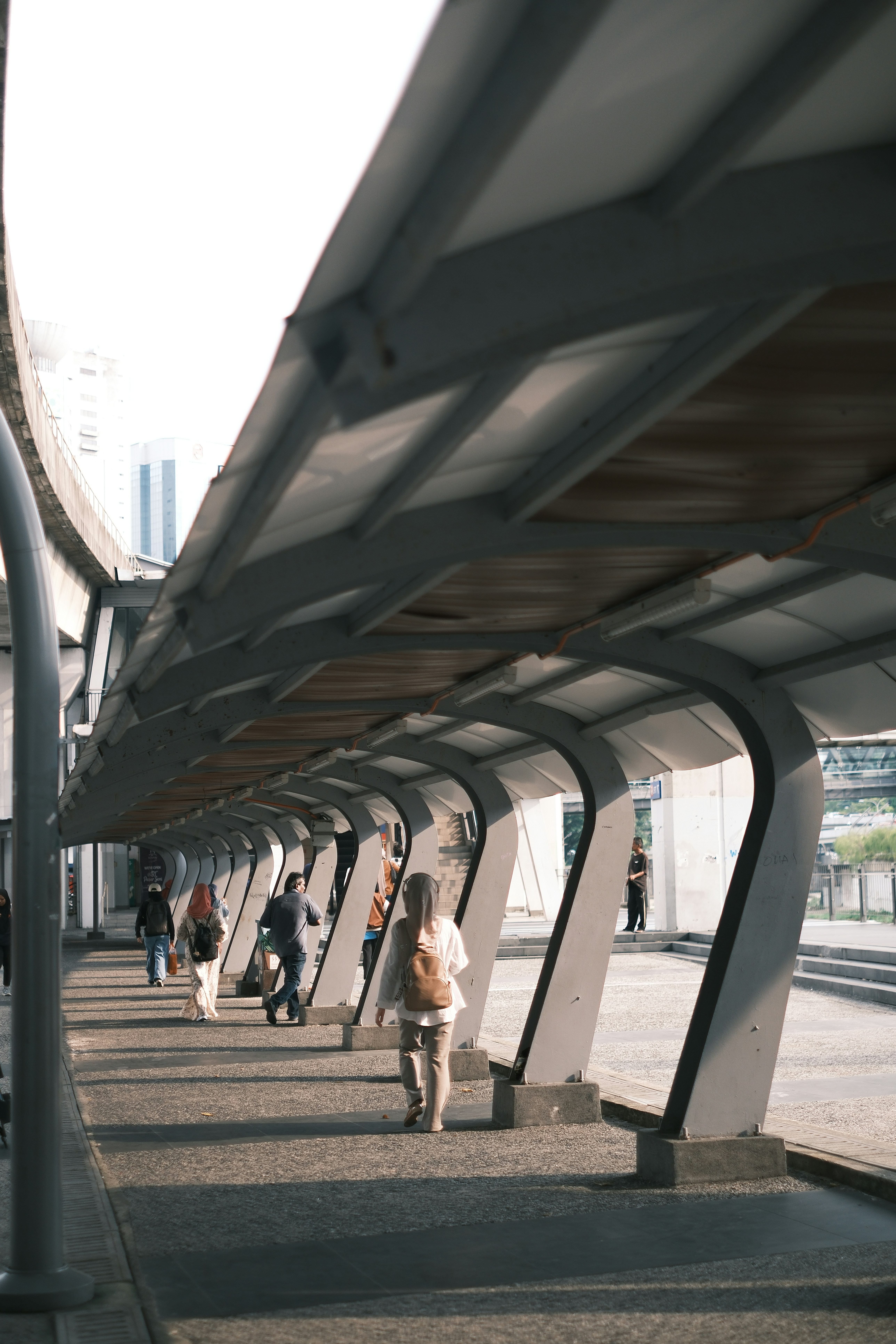 People walking under a covered walkway in a city.