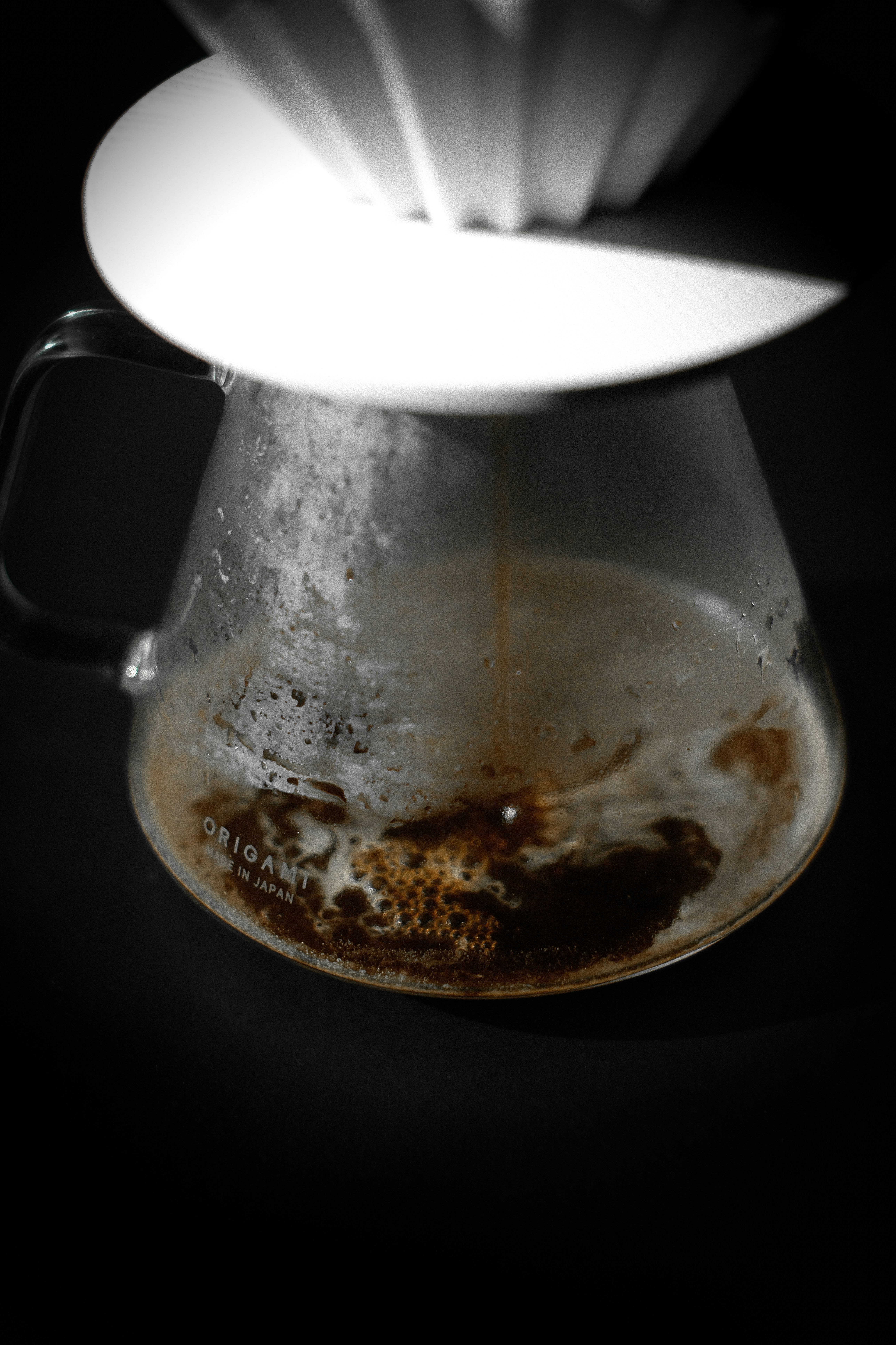 Coffee brewing in a glass carafe with a filter.