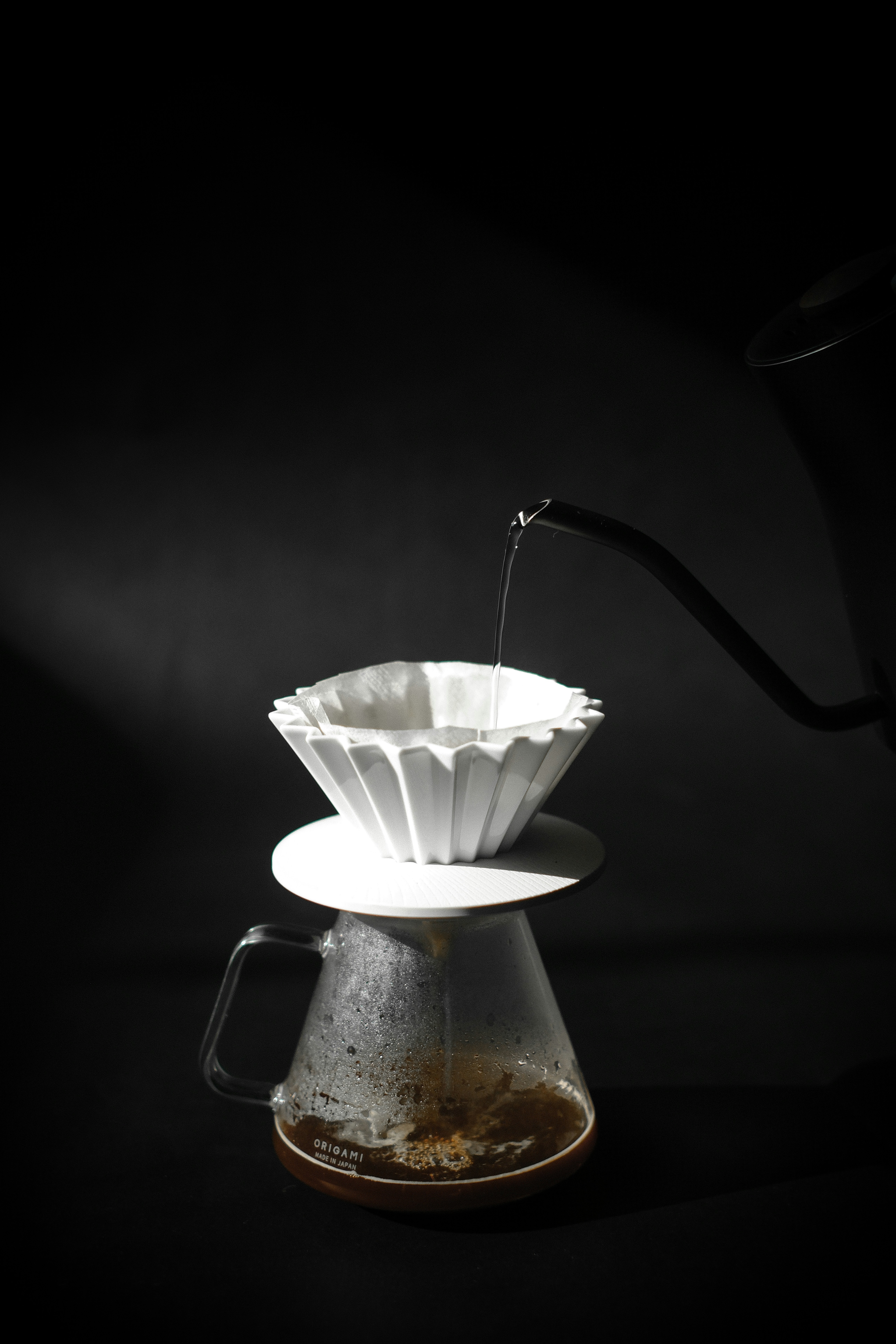 Pouring hot water over coffee grounds in a pour-over brewer.