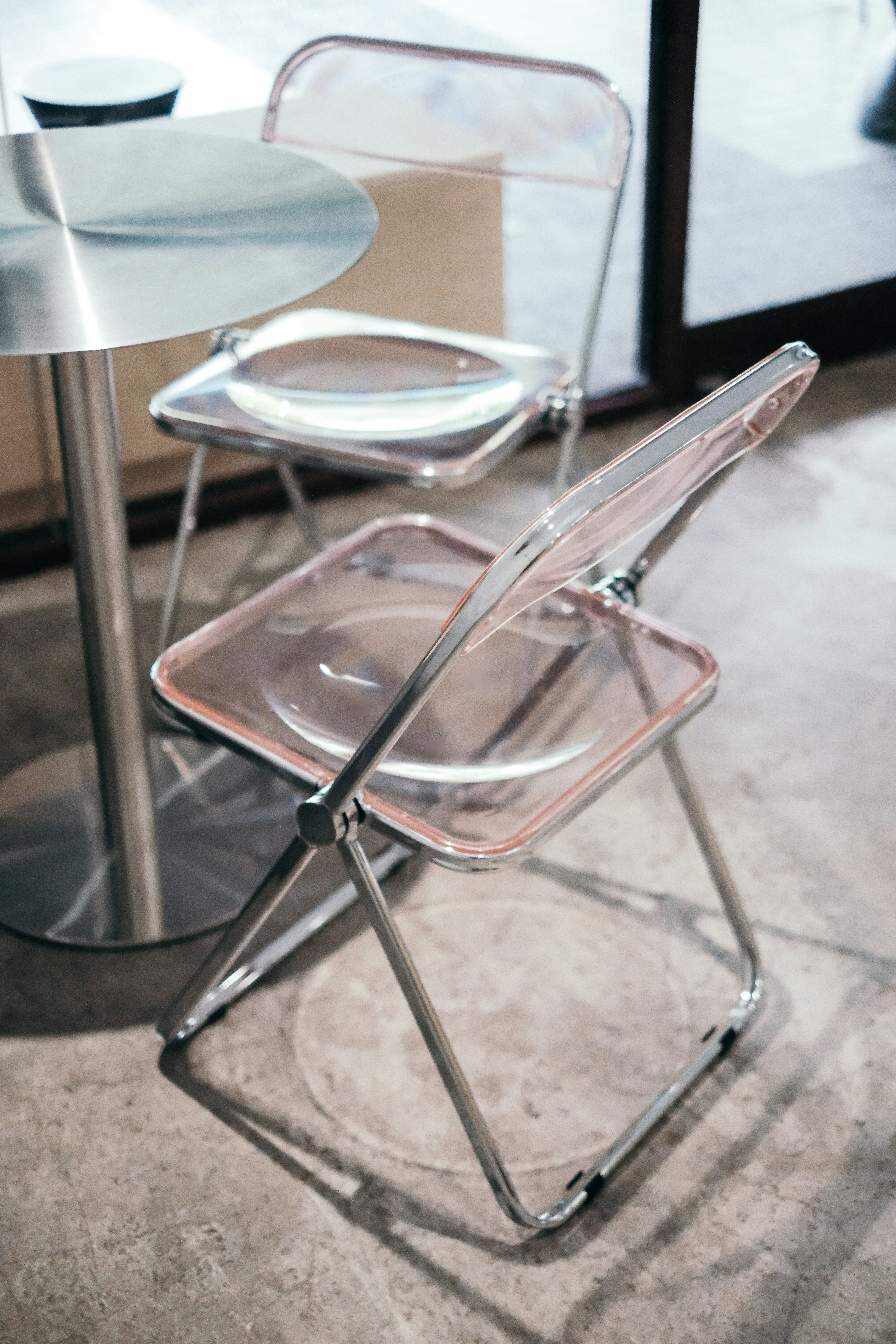 Two transparent chairs and a metal table