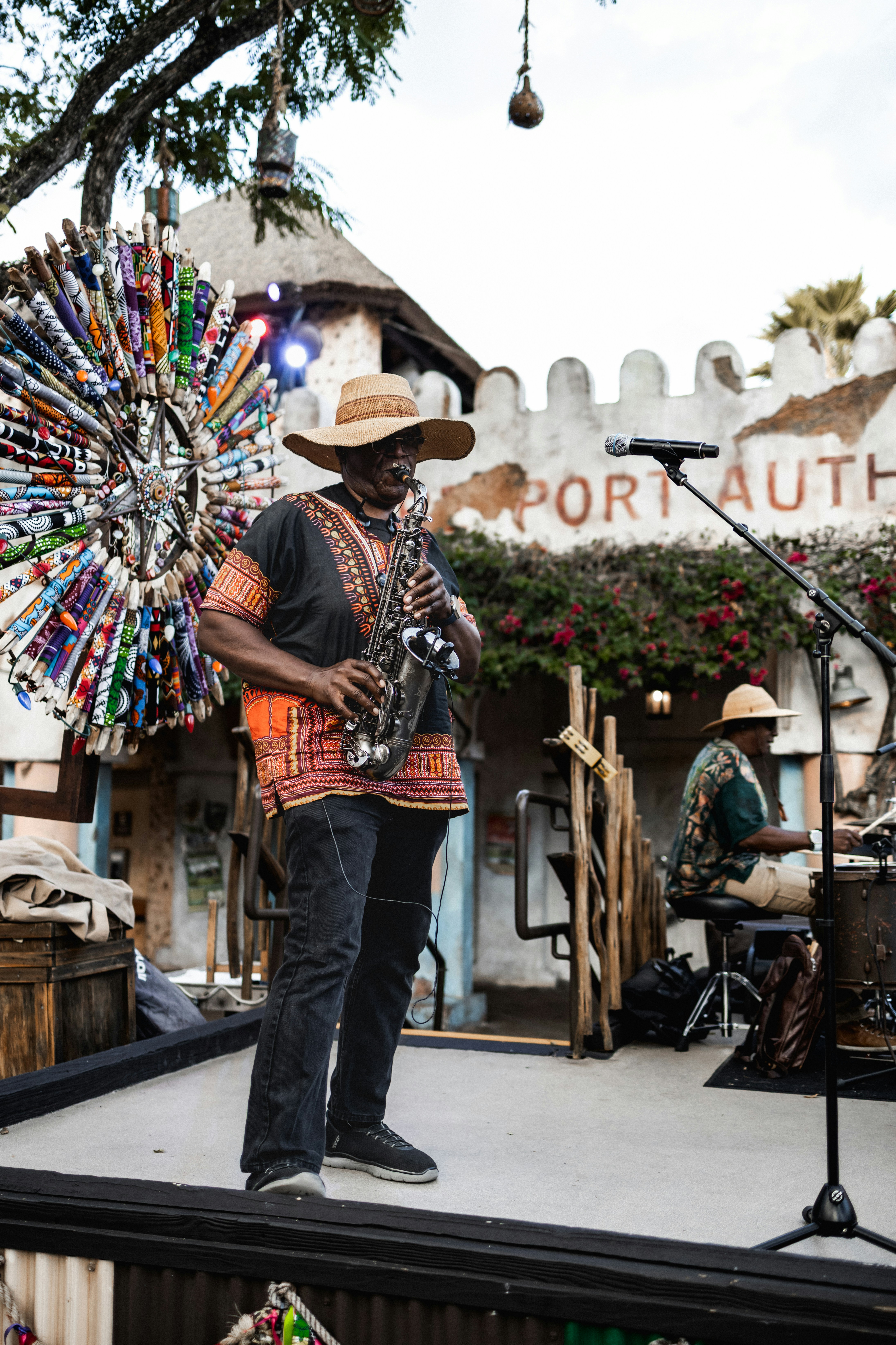 Man playing saxophone on a stage at an outdoor festival.