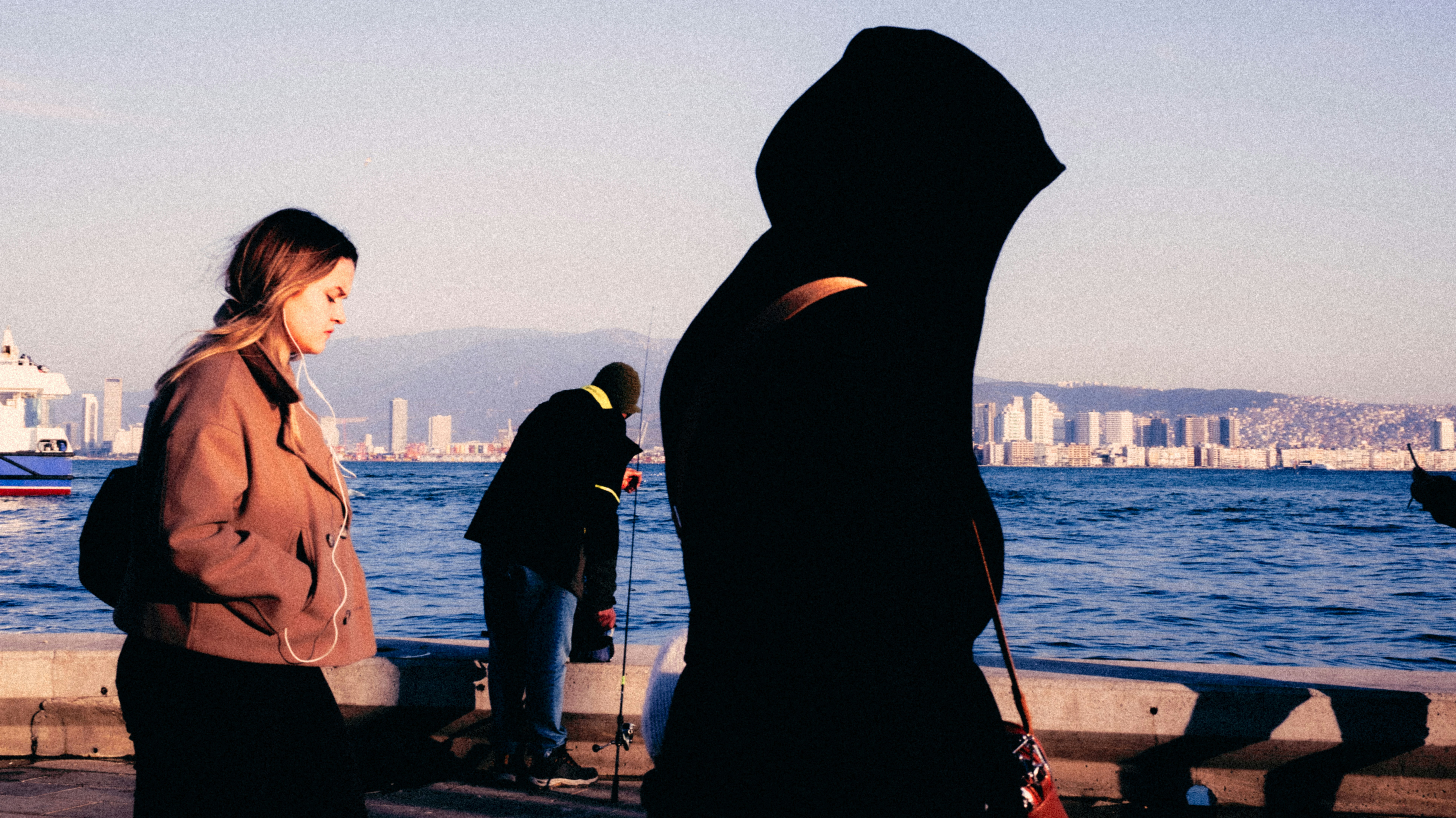 Orang-orang di tepi air dengan cakrawala kota