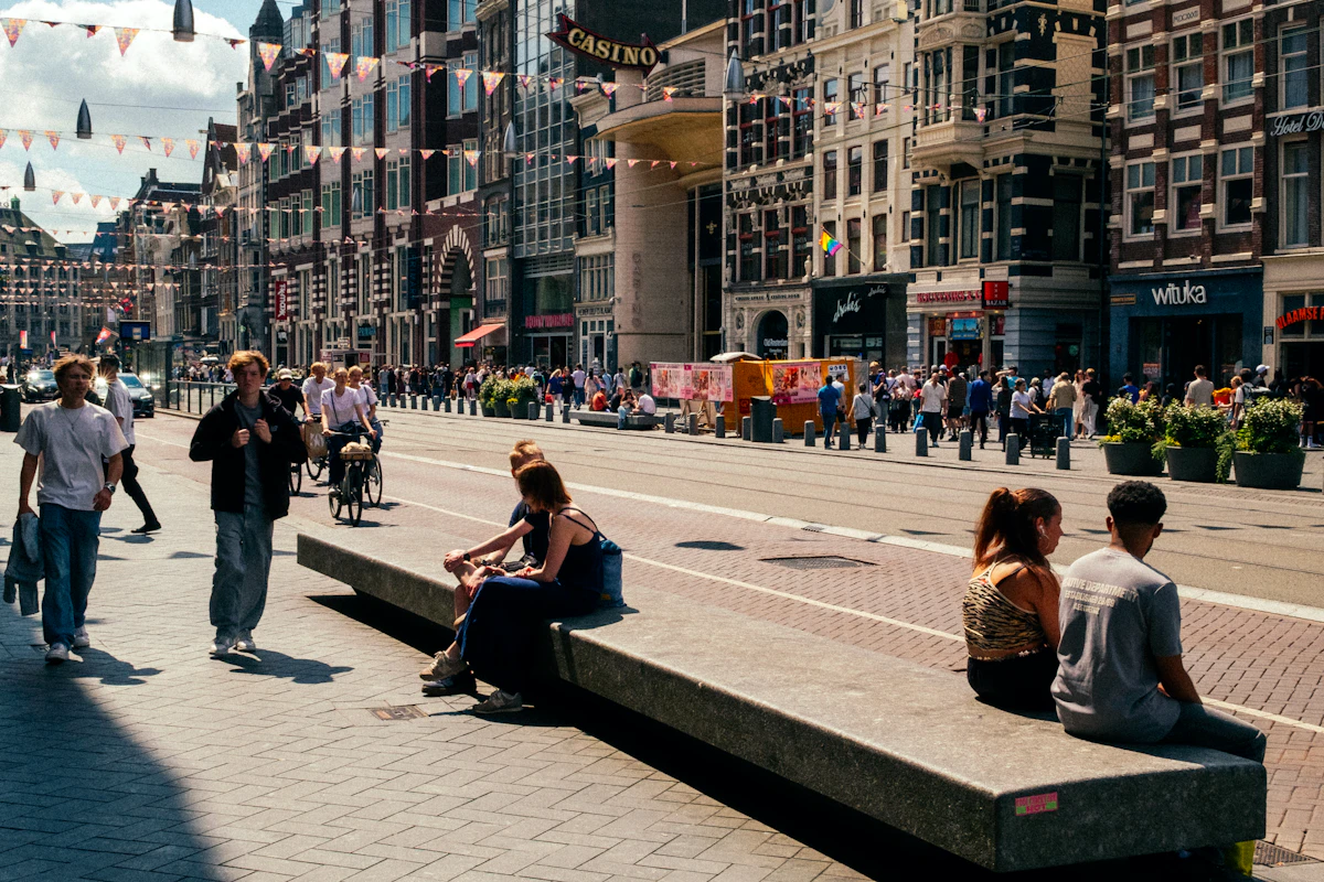 Pedestrians crossing under city buildings with hard side light