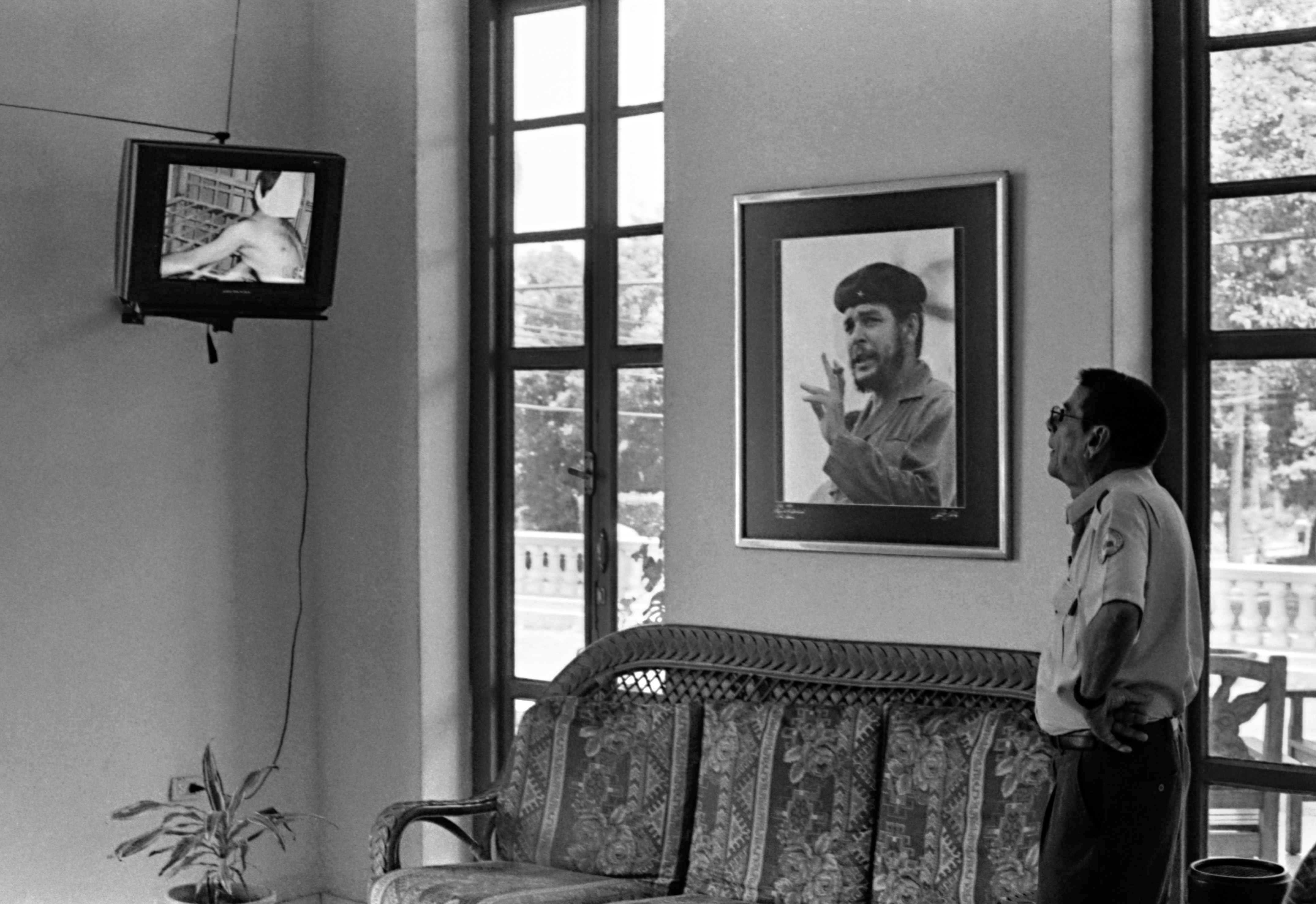 Man watches television next to portrait.