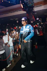 Man in racing jacket walks through a crowd