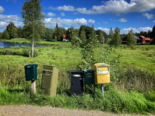 Mailboxes stand in a grassy field with a village background
