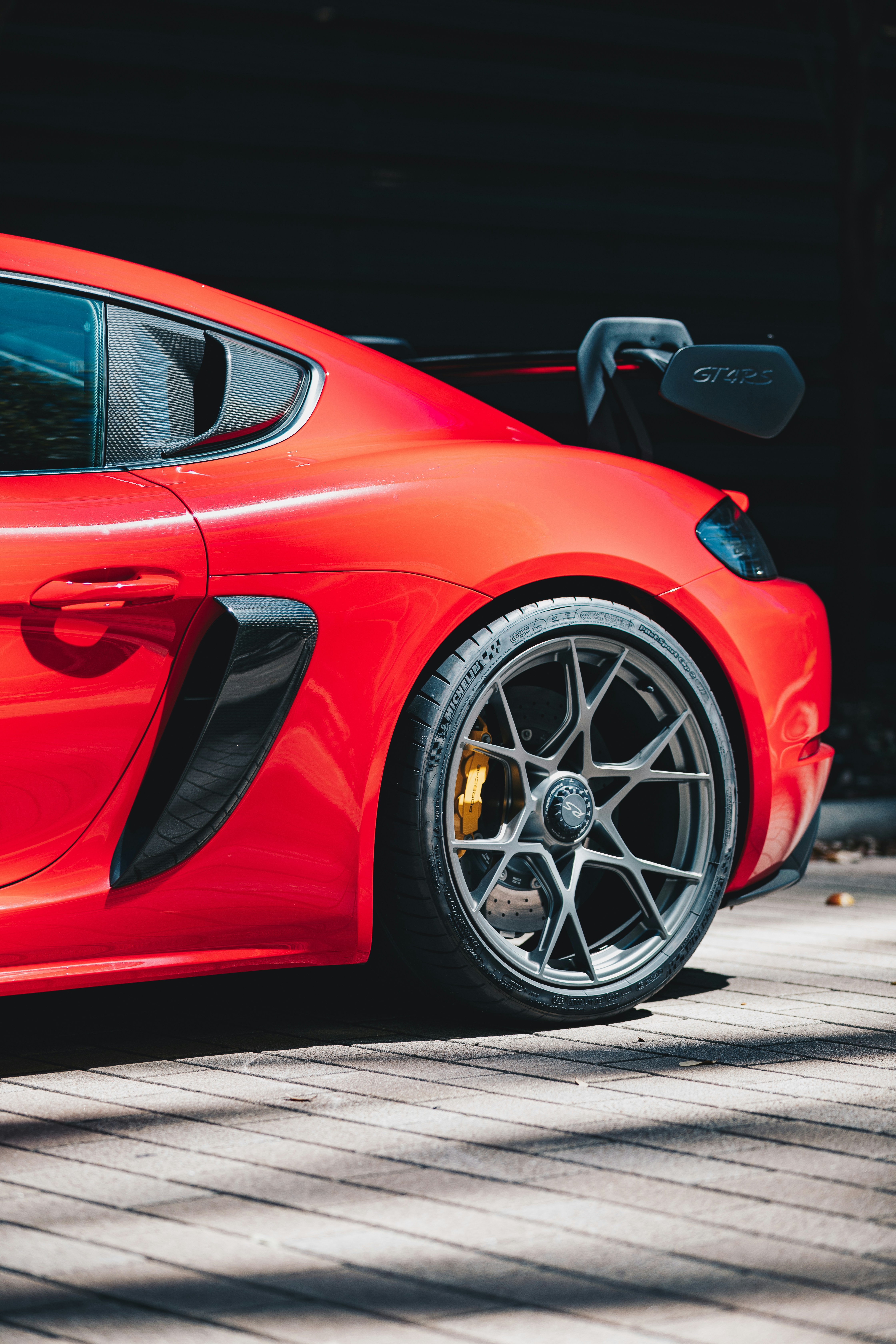 Nahaufnahme des Hinterrads und des Spoilers eines roten Sportwagens.