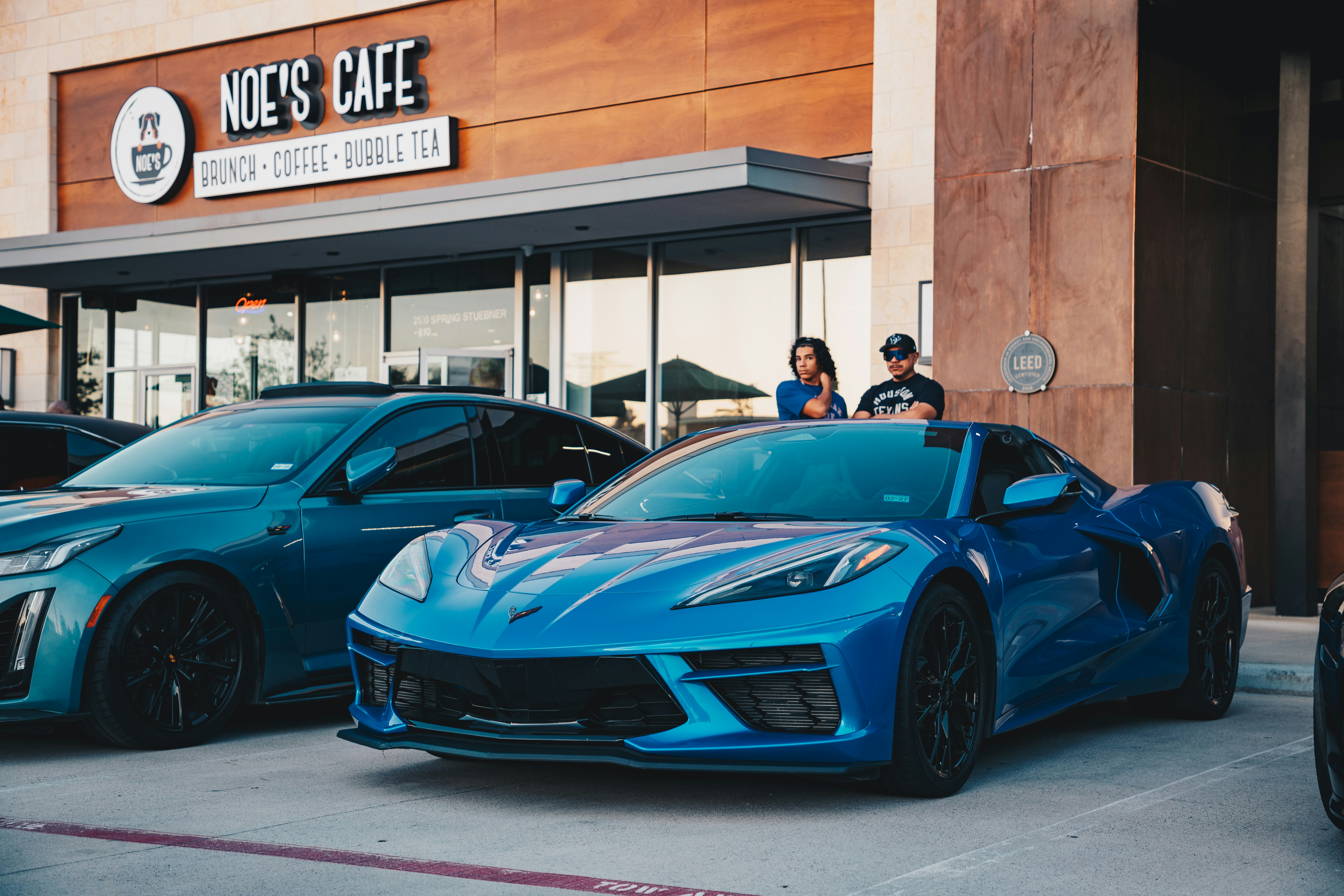 Zwei blaue Sportwagen parkten vor einem Café.