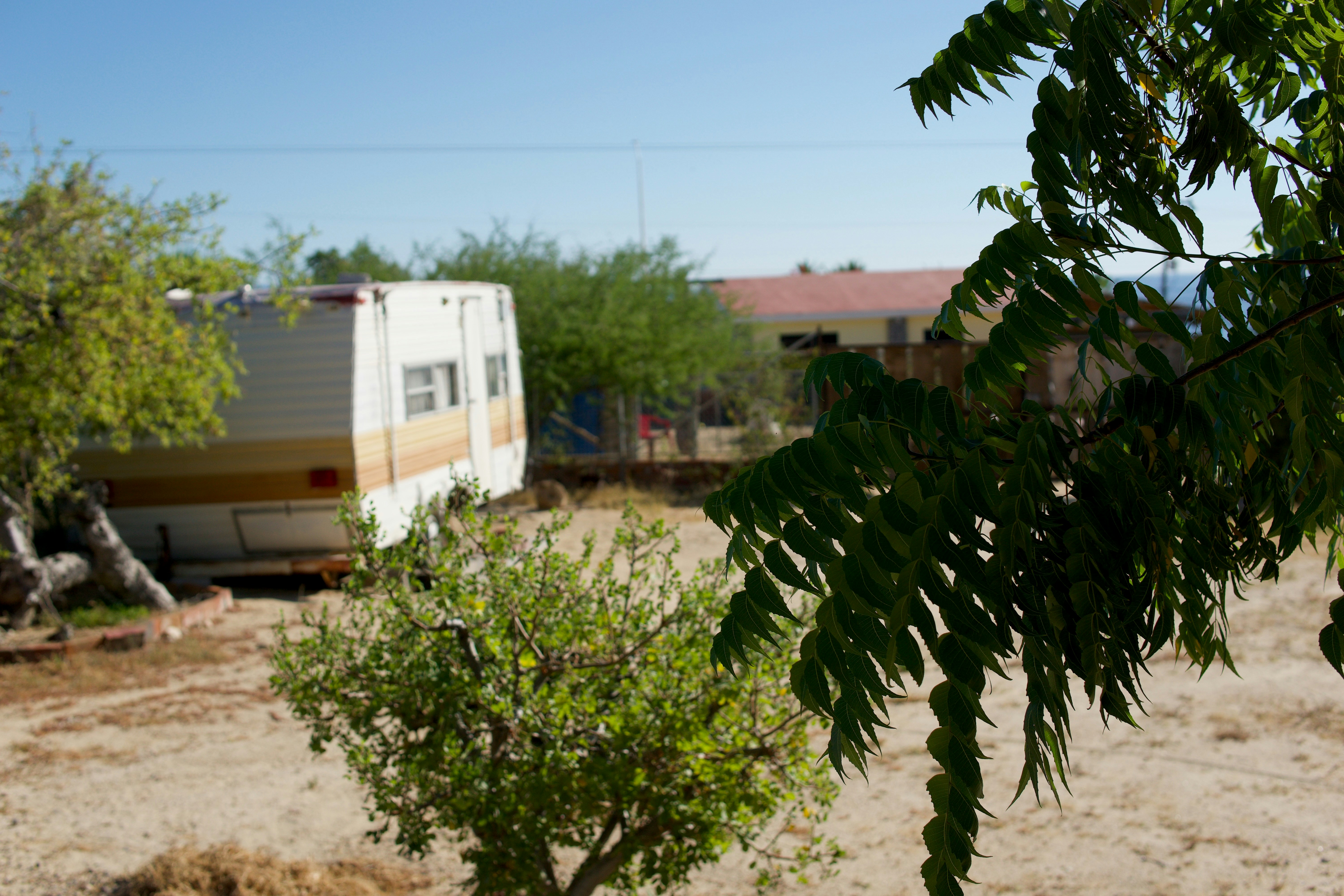 An old trailer sits in a dry, dusty yard.