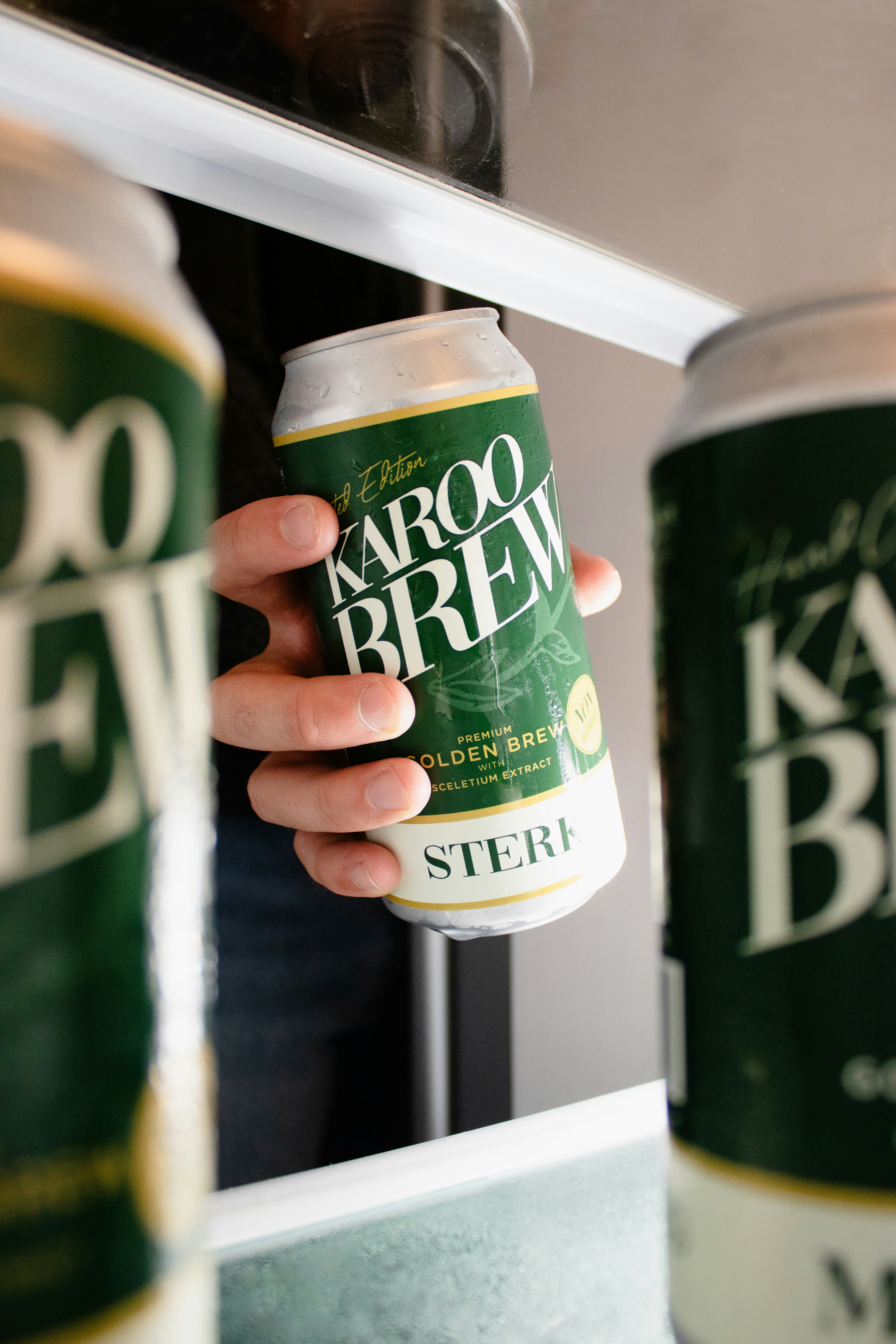 Hand reaching for a karoo brew beer can in refrigerator