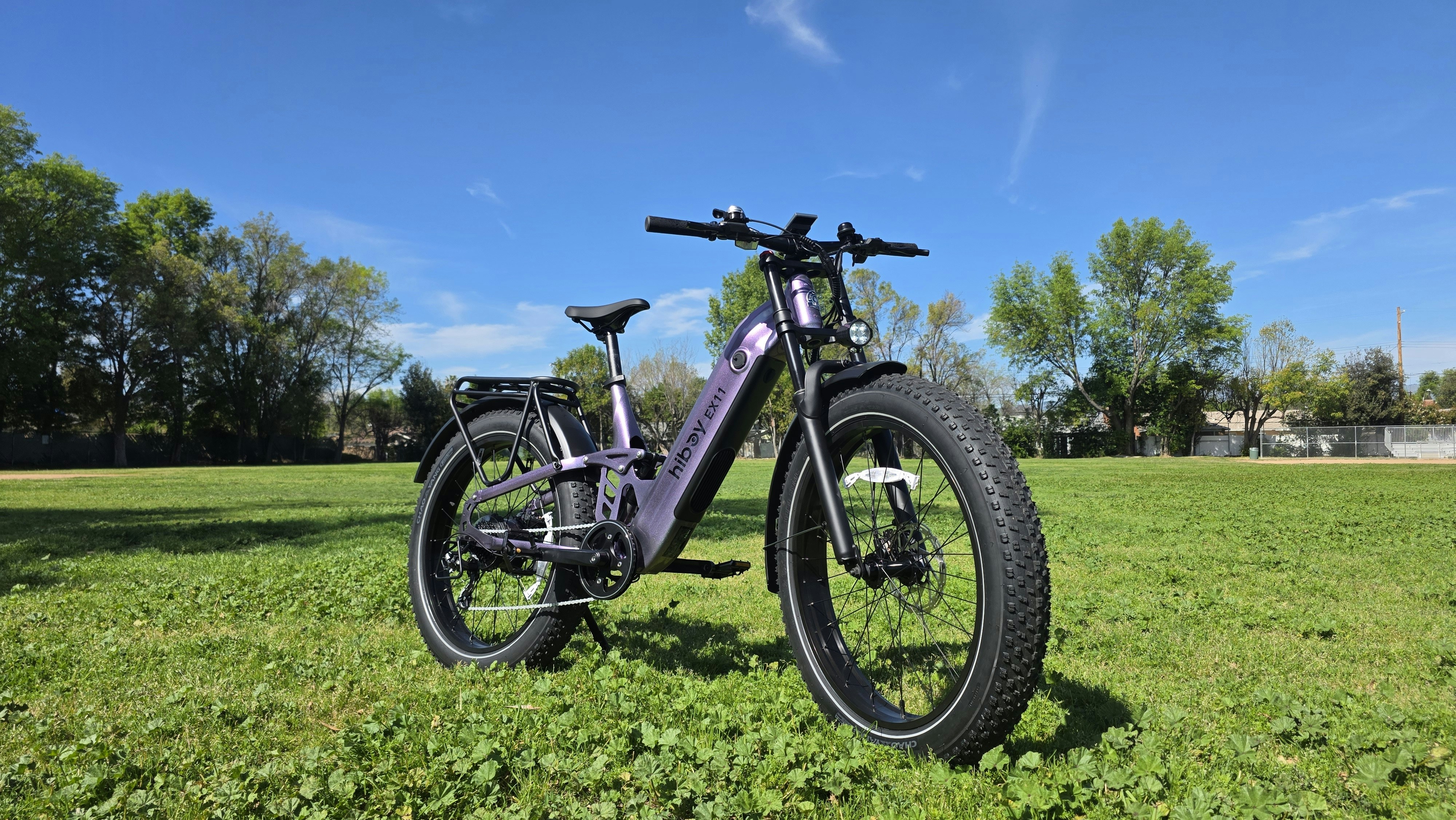 A purple electric bicycle parked on a grassy field.