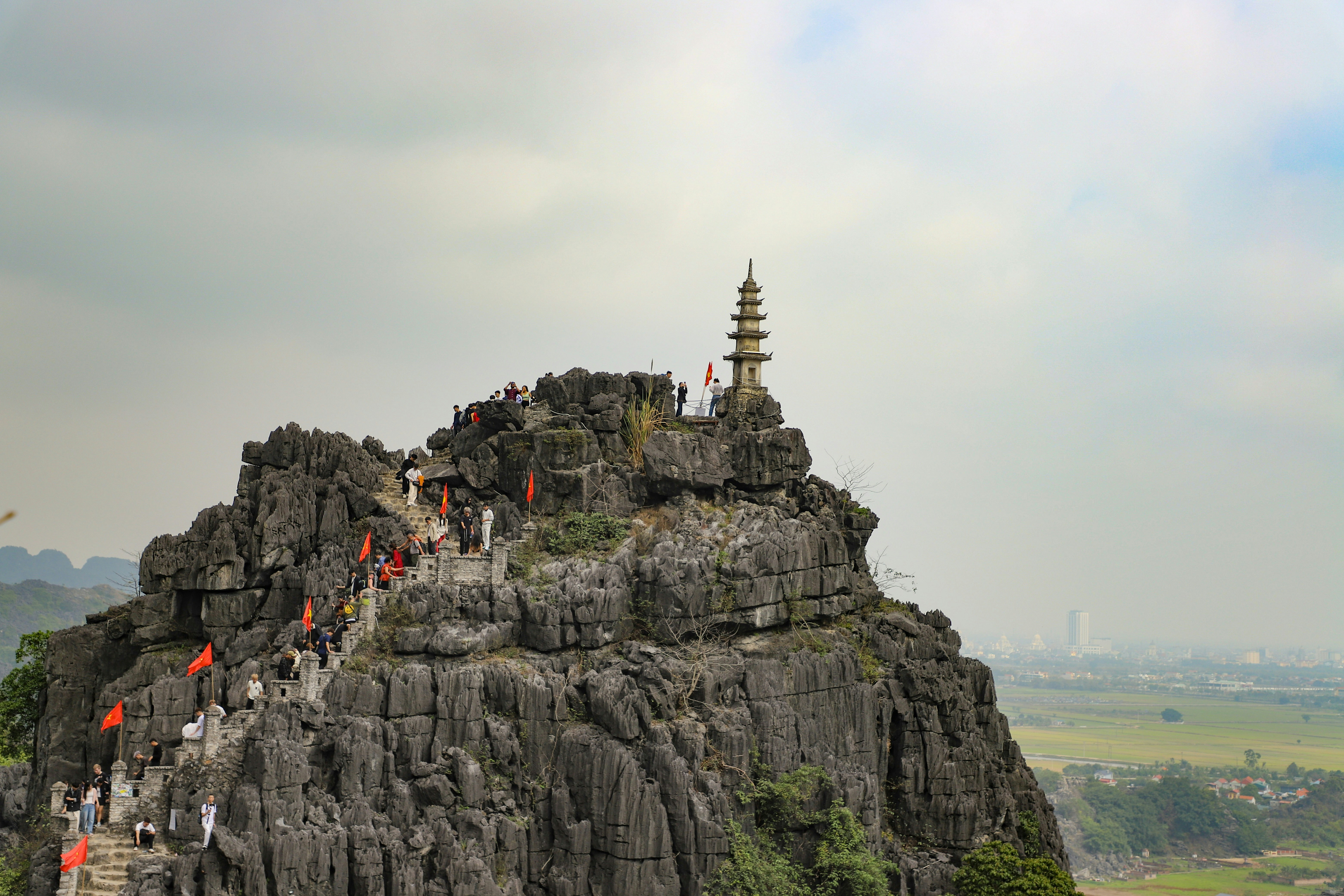 Gente escalando una montaña rocosa hasta una pagoda