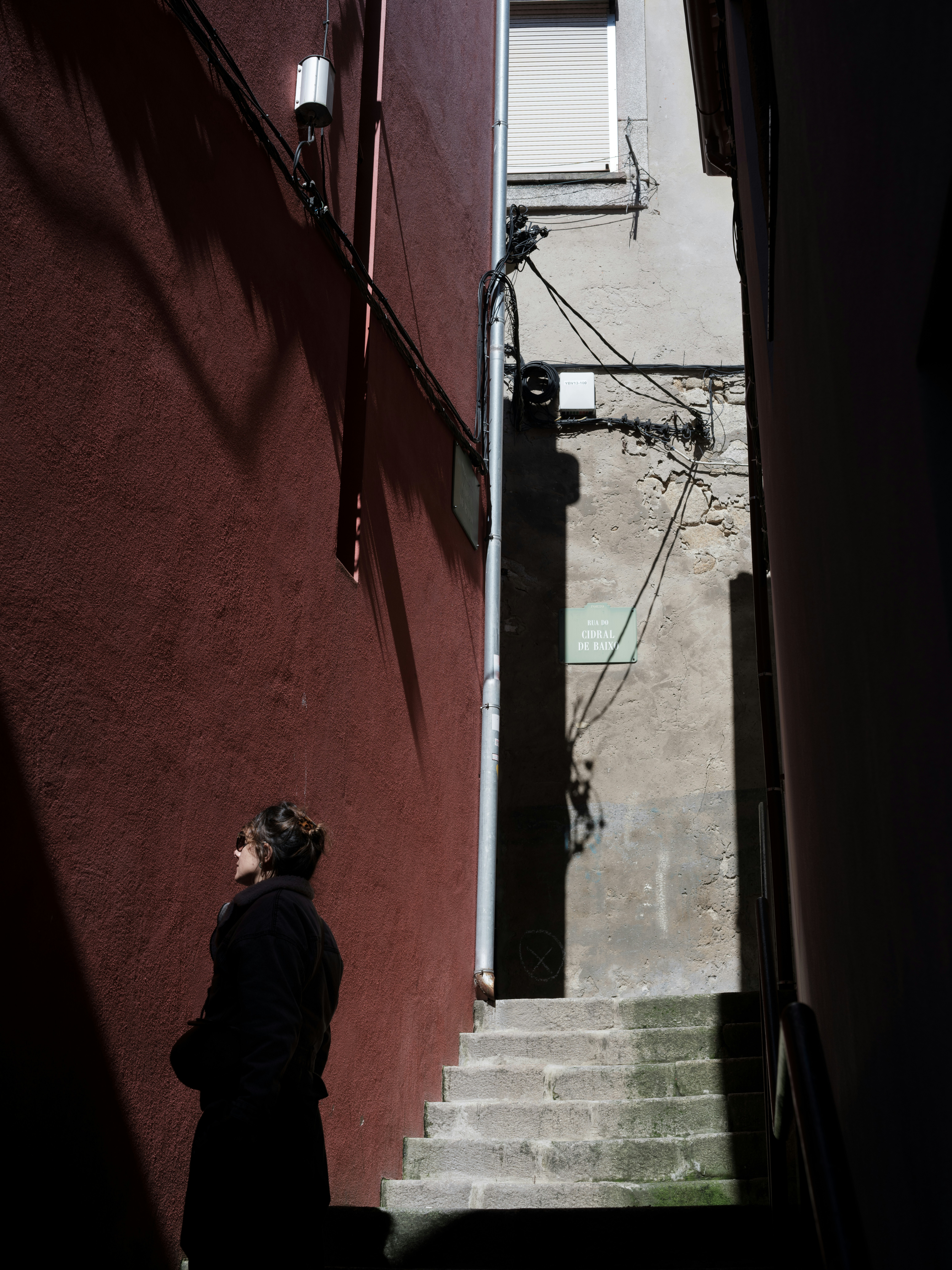 A person stands at the bottom of a narrow staircase.