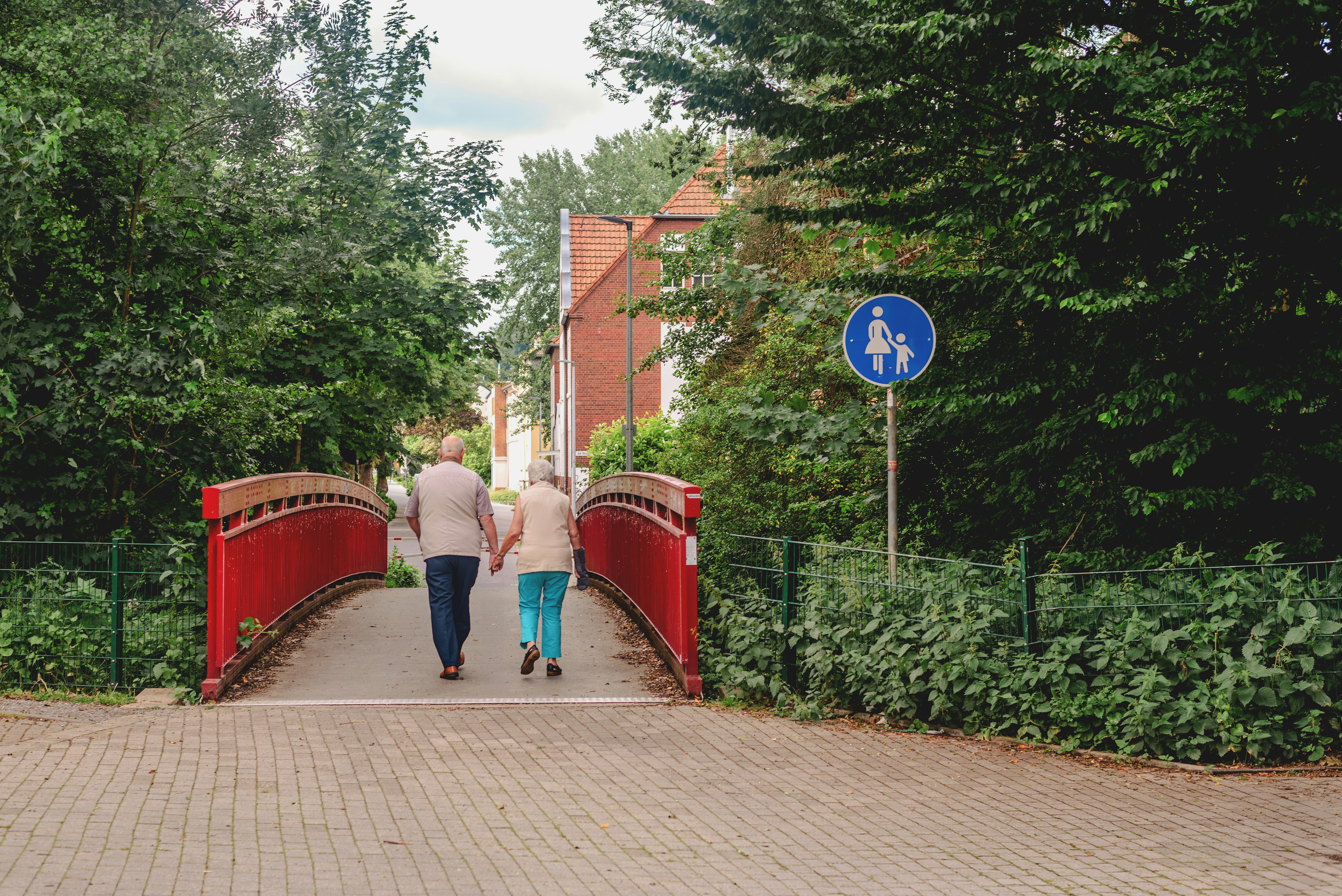 elderly couple walking across a bridge