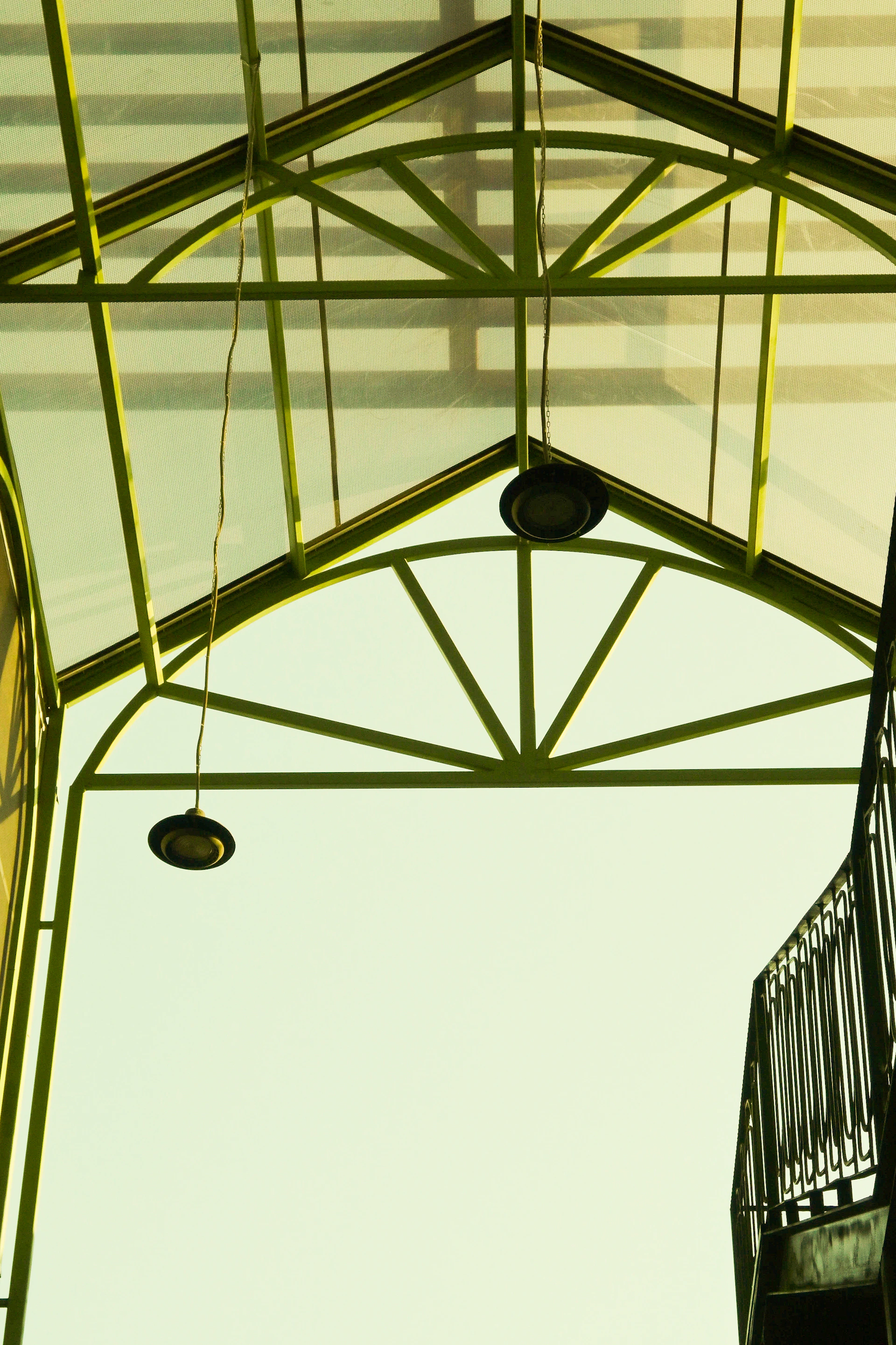 Green metal structure with hanging lights against sky