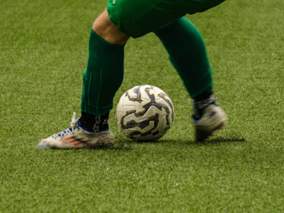 A soccer player kicking a ball on a green field