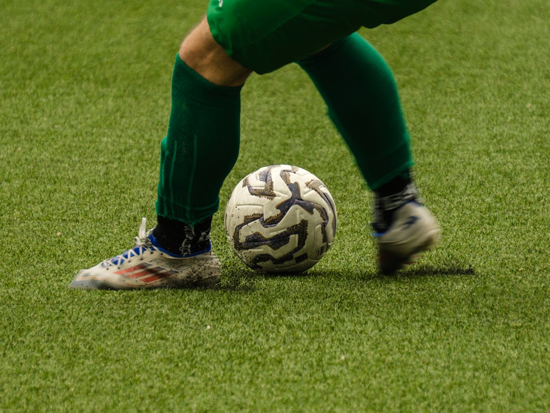 A soccer player kicking a ball on a green field