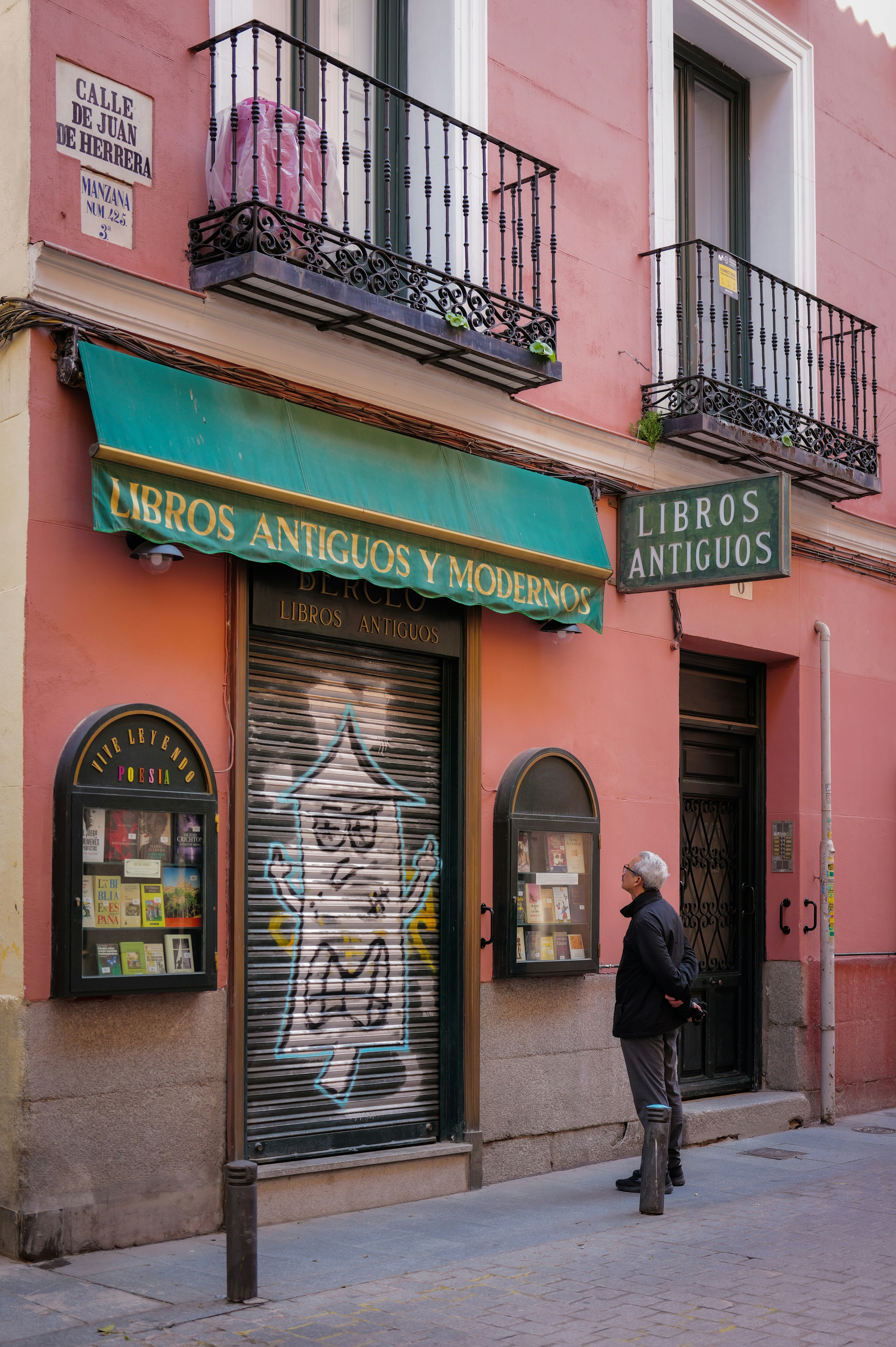 Man looks at a pink building with a bookshop.