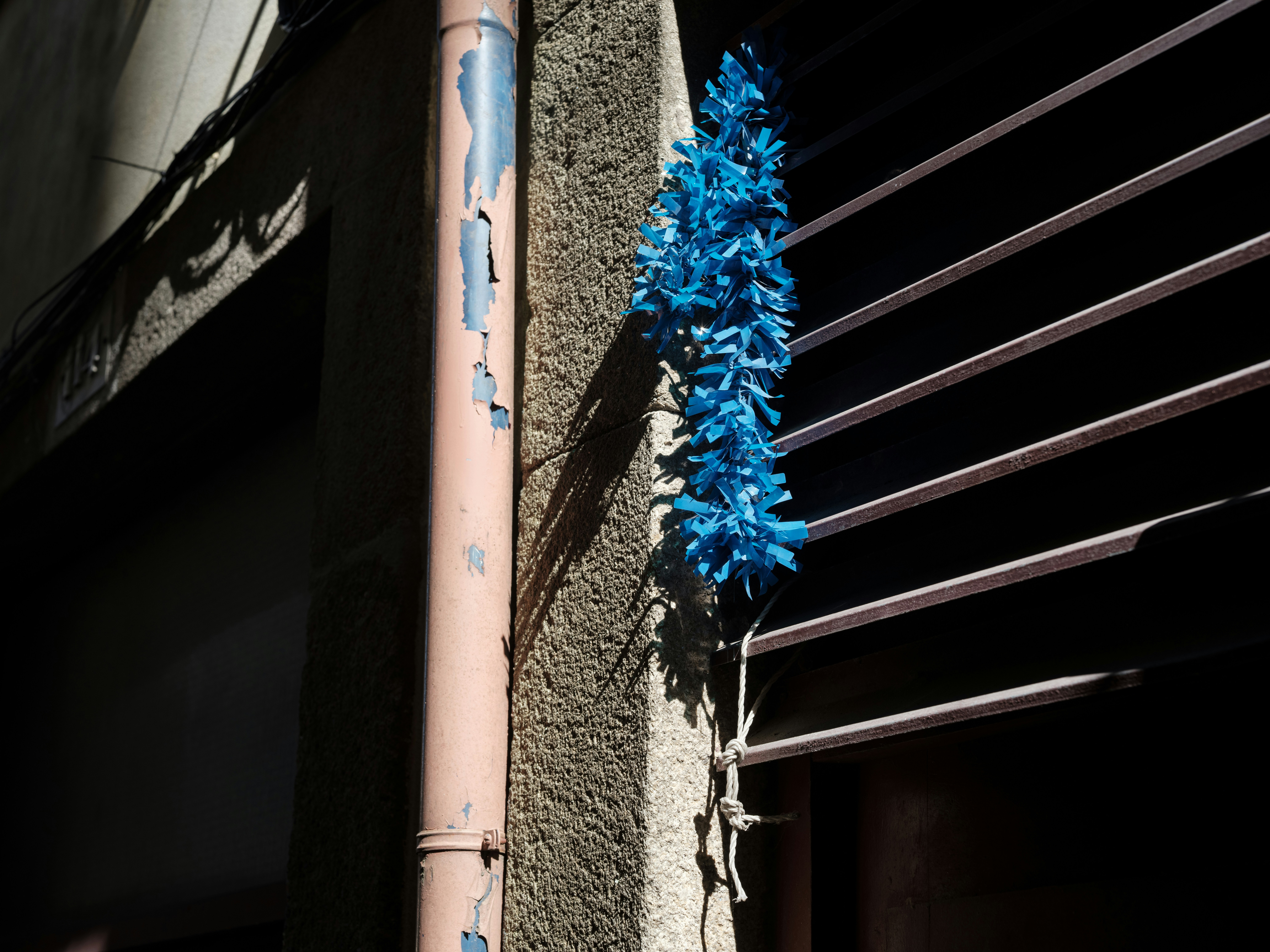 Bright blue garland hangs on a textured wall.