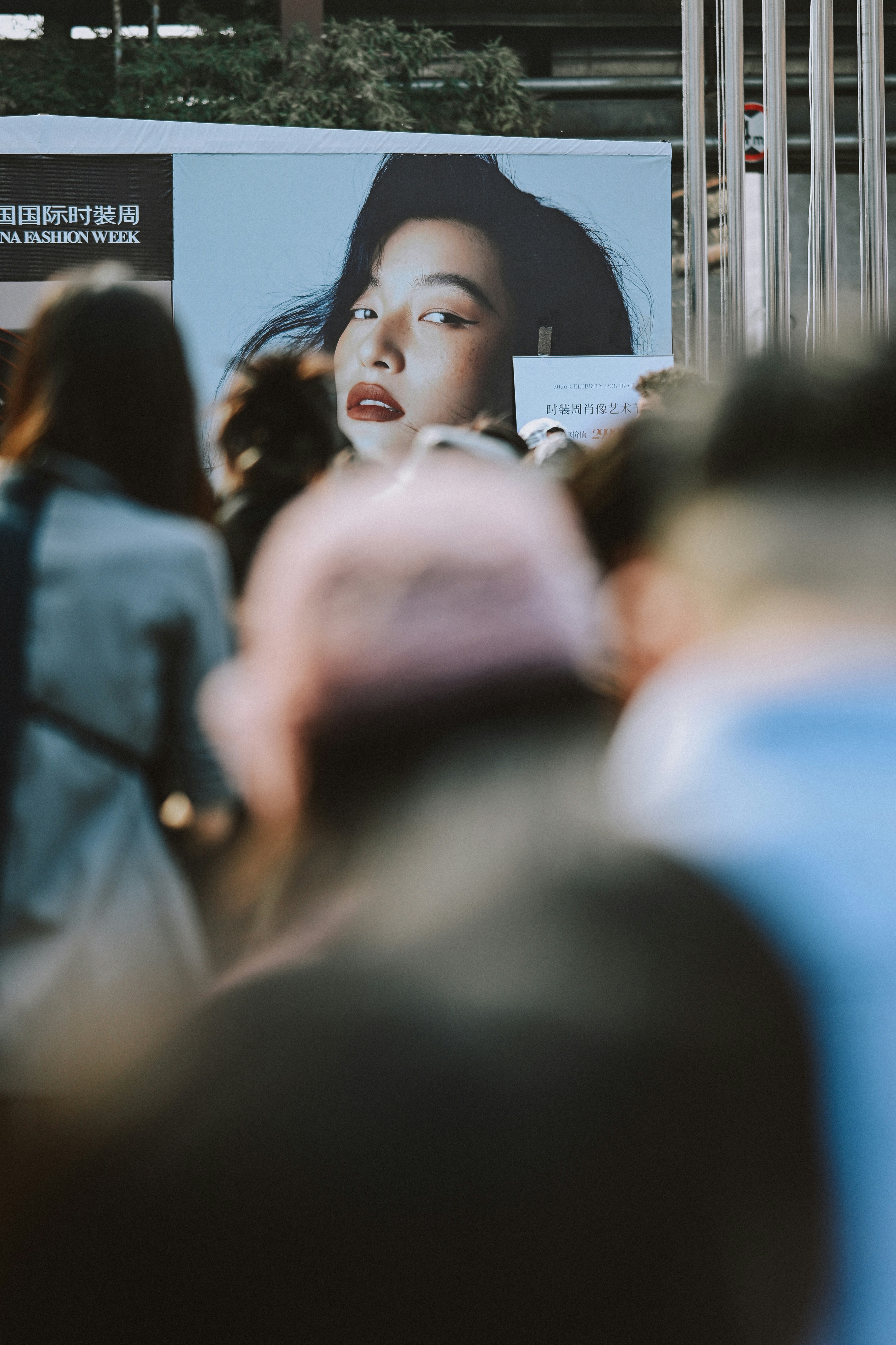 Rosto de mulher em um outdoor com multidão em primeiro plano
