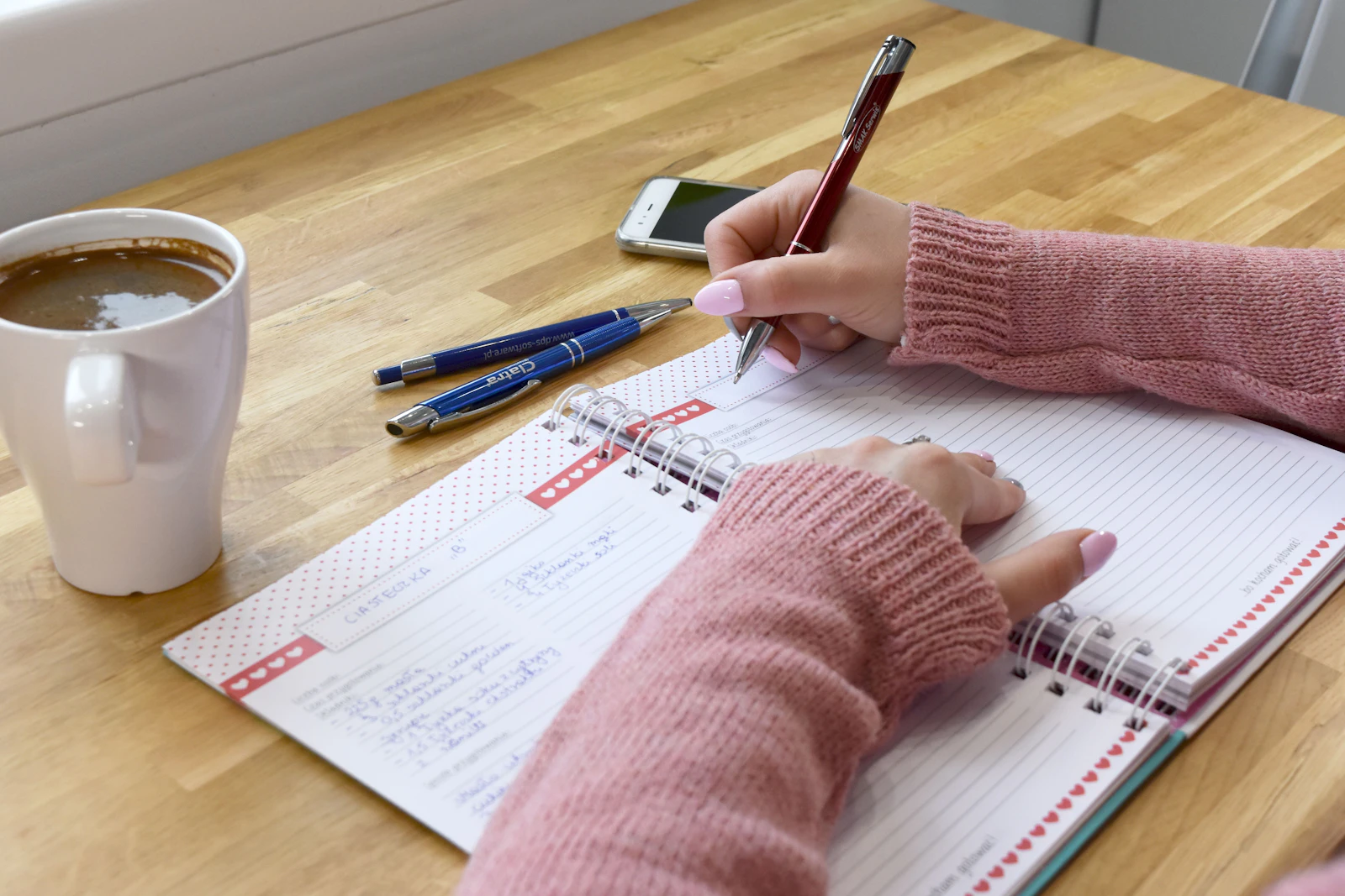 Person schreibt neben einer Tasse Kaffee in ein Notizbuch und gestaltet ein neues Morgenritual