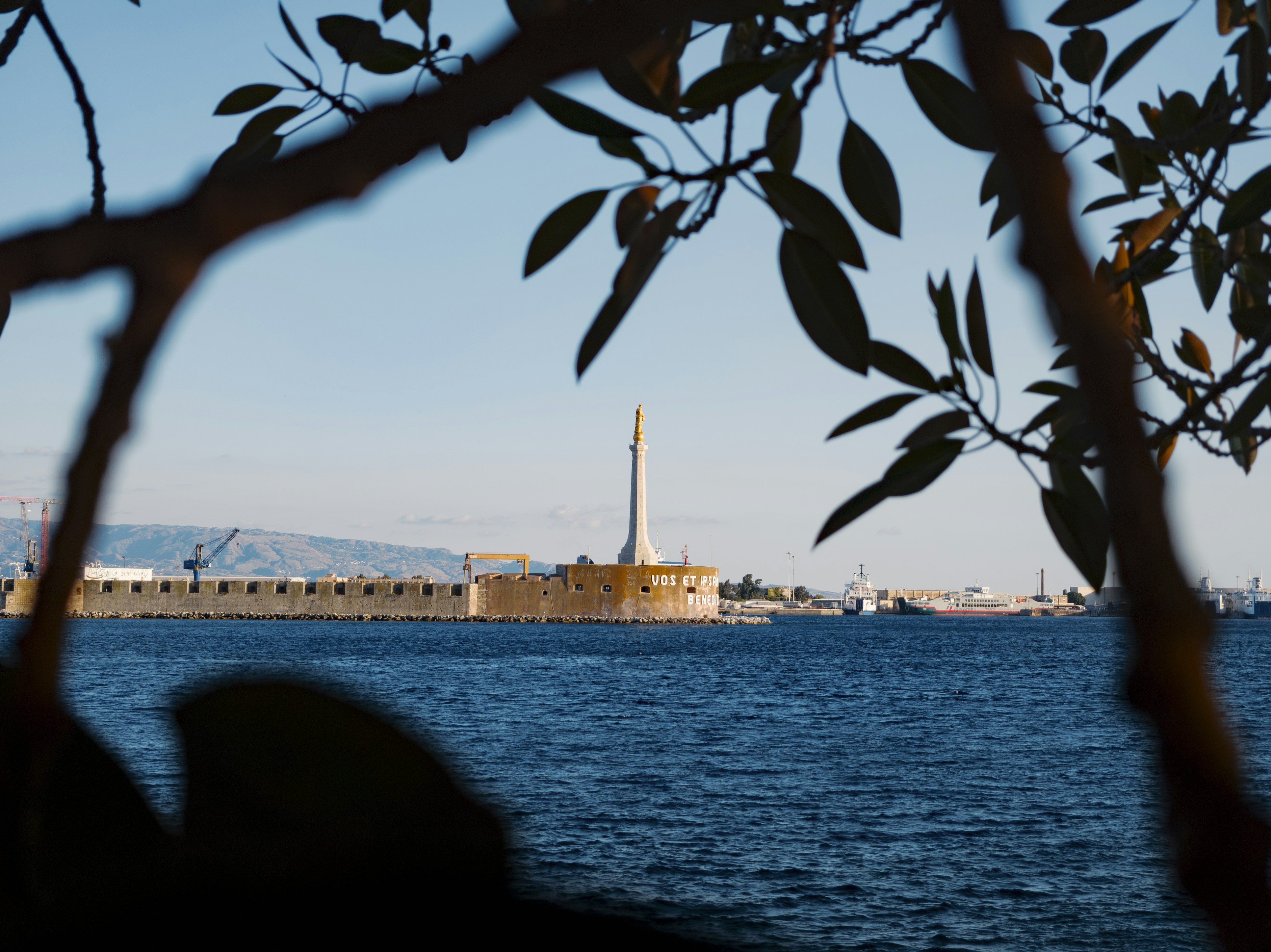 Monumento lontano su un lungomare con mare blu.