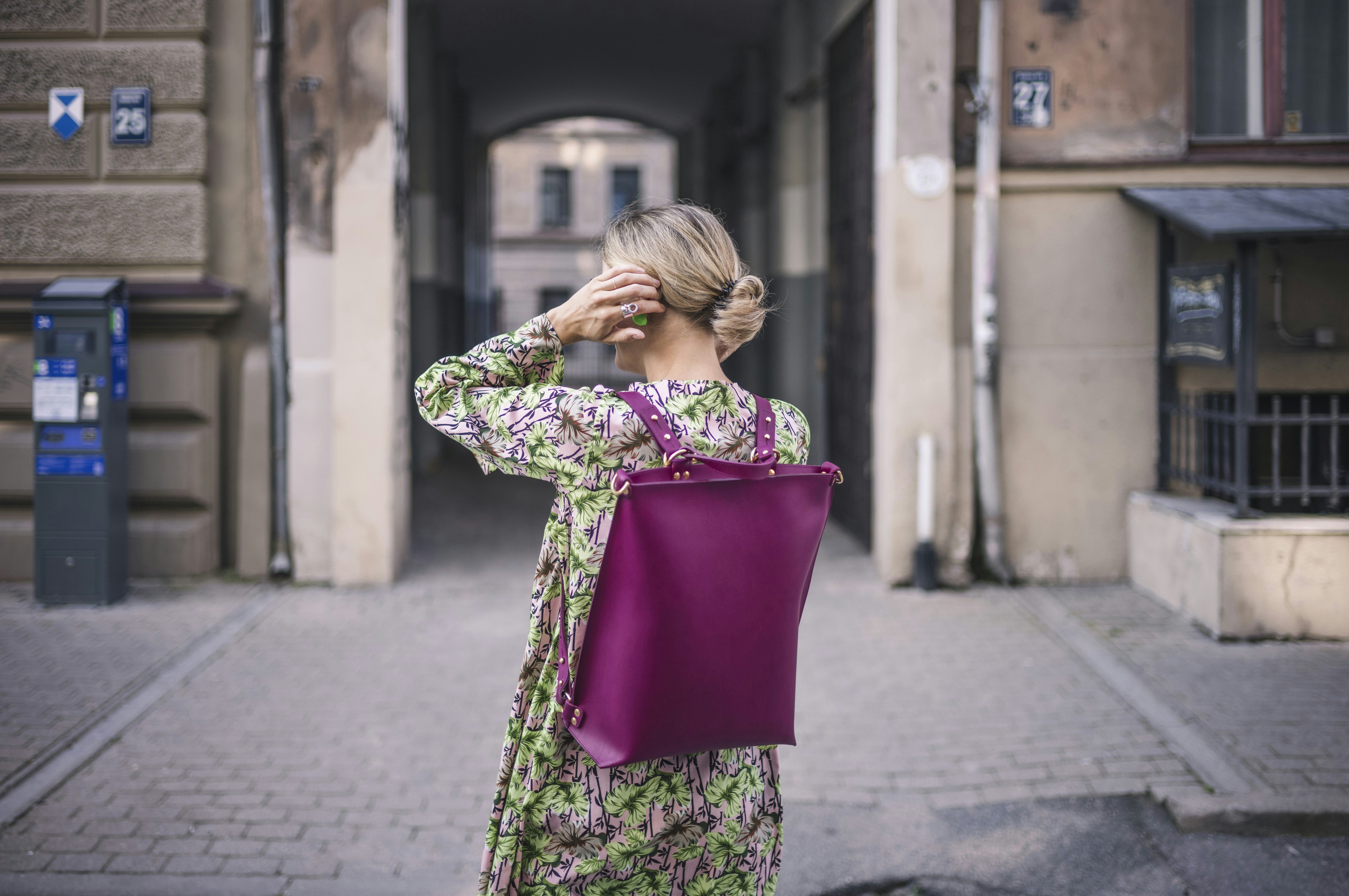 Woman with magenta backpack walks down alley