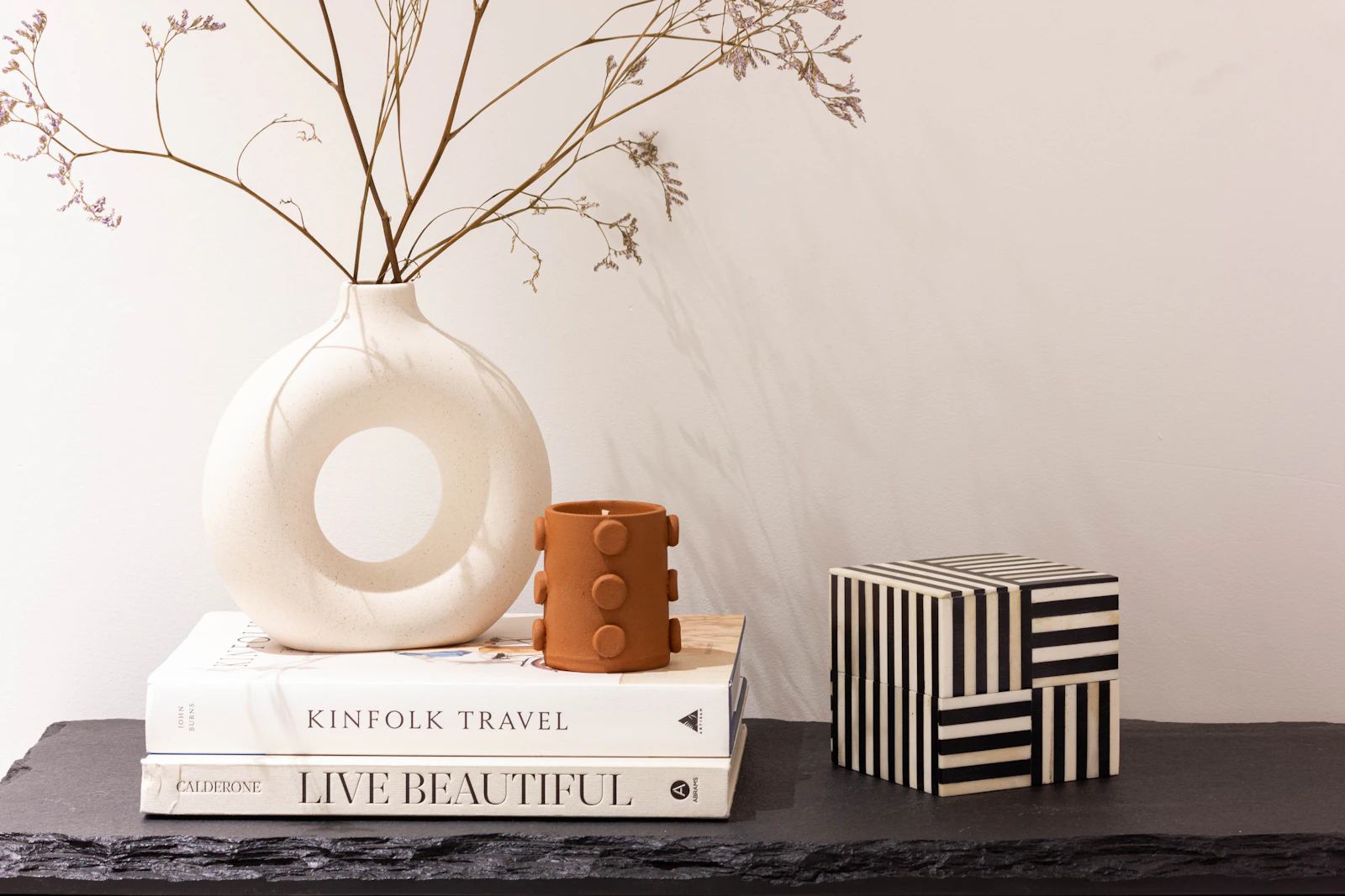 Curated decorative objects, sculptural ceramics and books styled in a refined neutral setting
