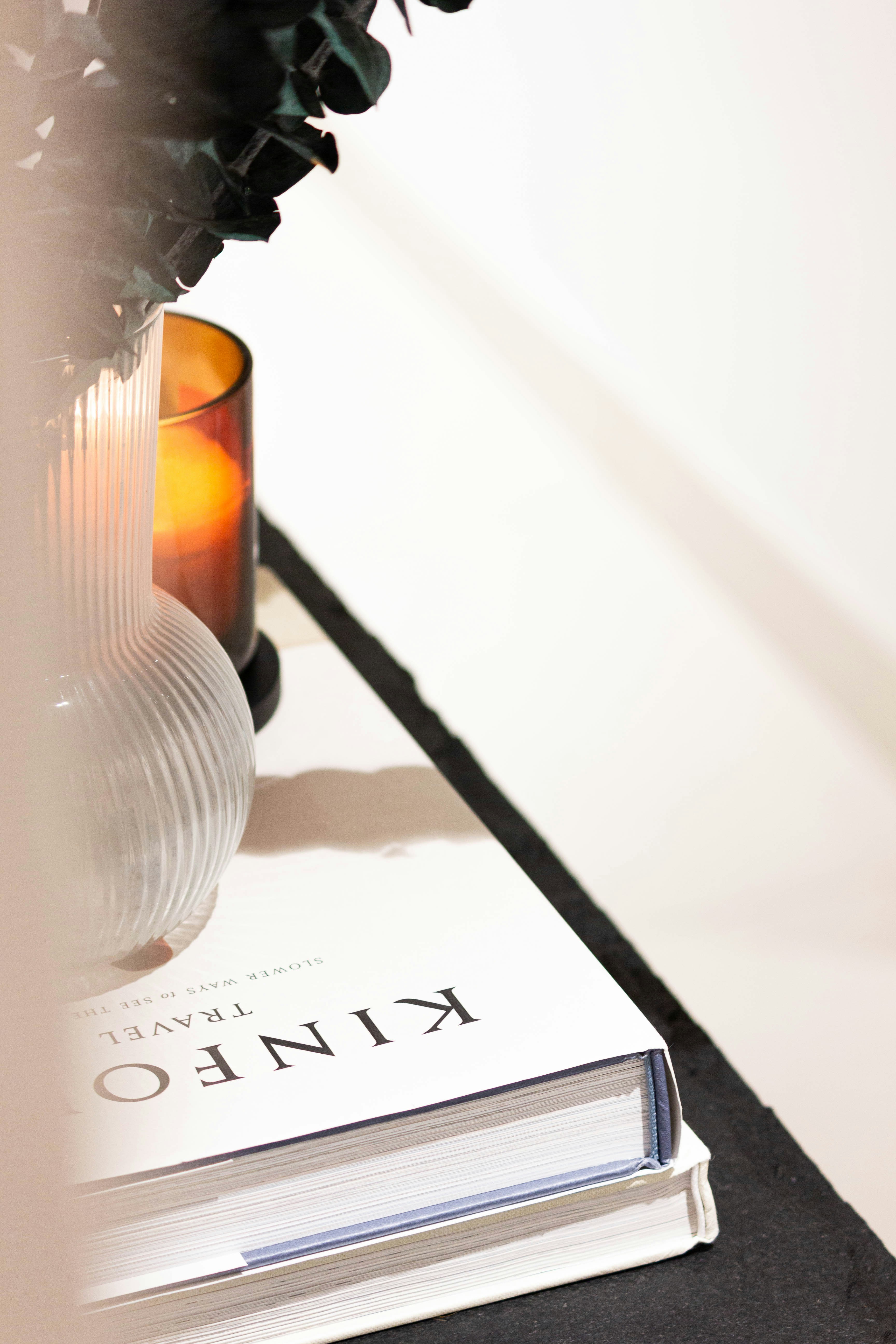 Una vela encendida junto a un libro sobre una superficie.
