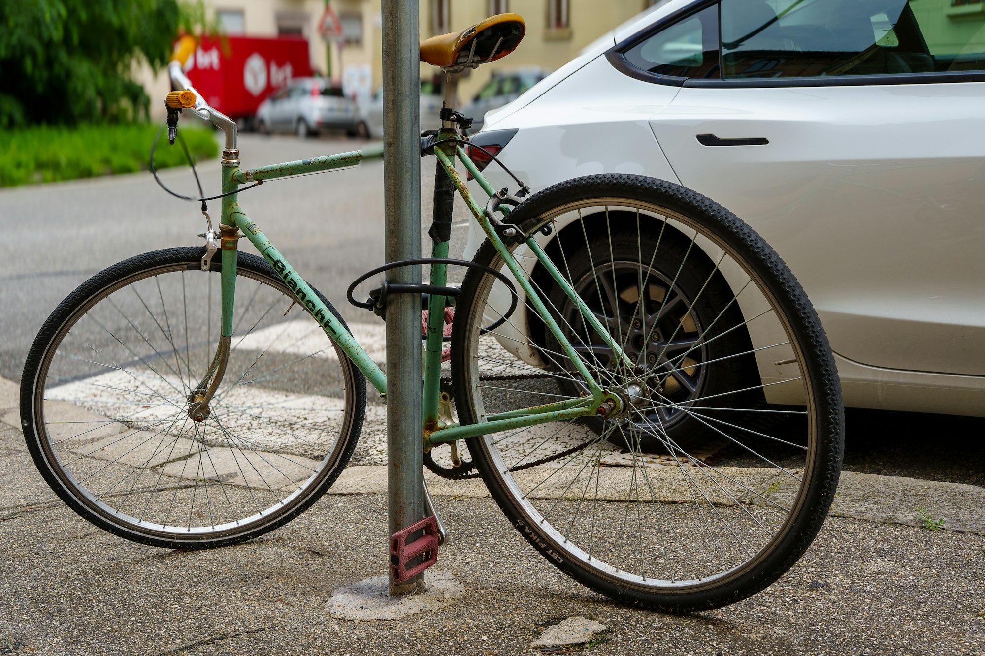 A vintage bicycle locked to a pole on a street.