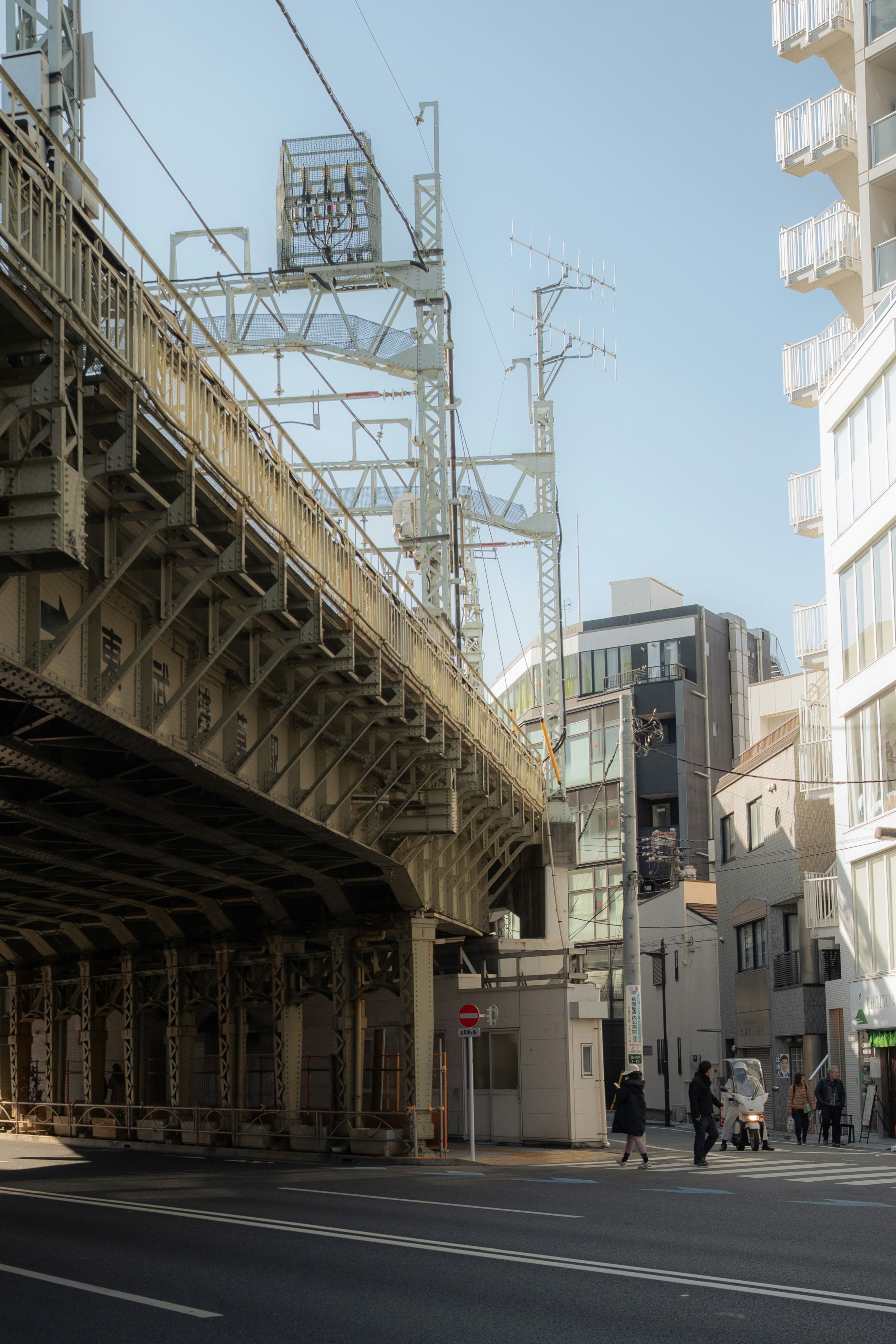 Elevated train tracks over a city street with buildings.