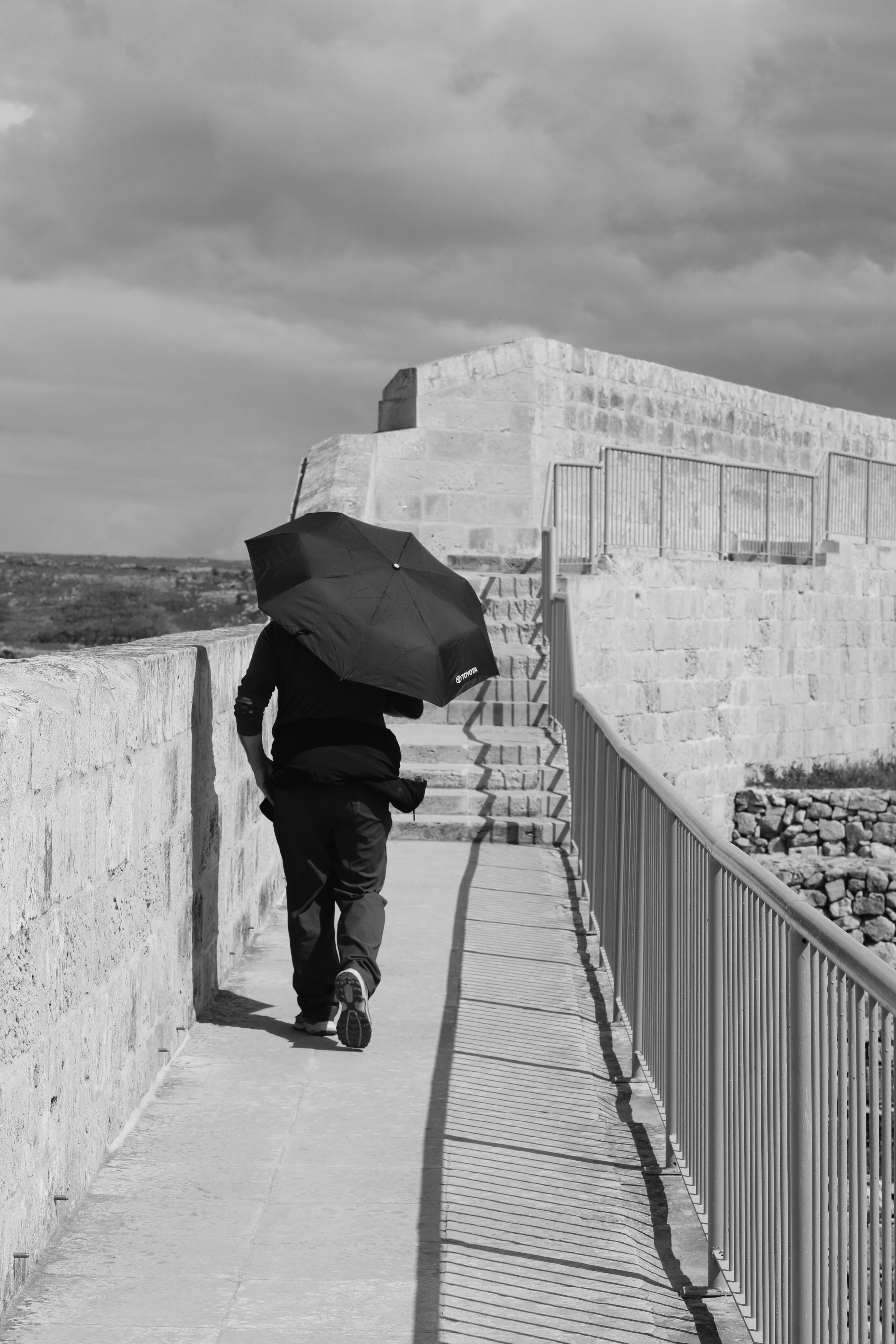 Person mit Regenschirm geht auf dem Steinmauerweg