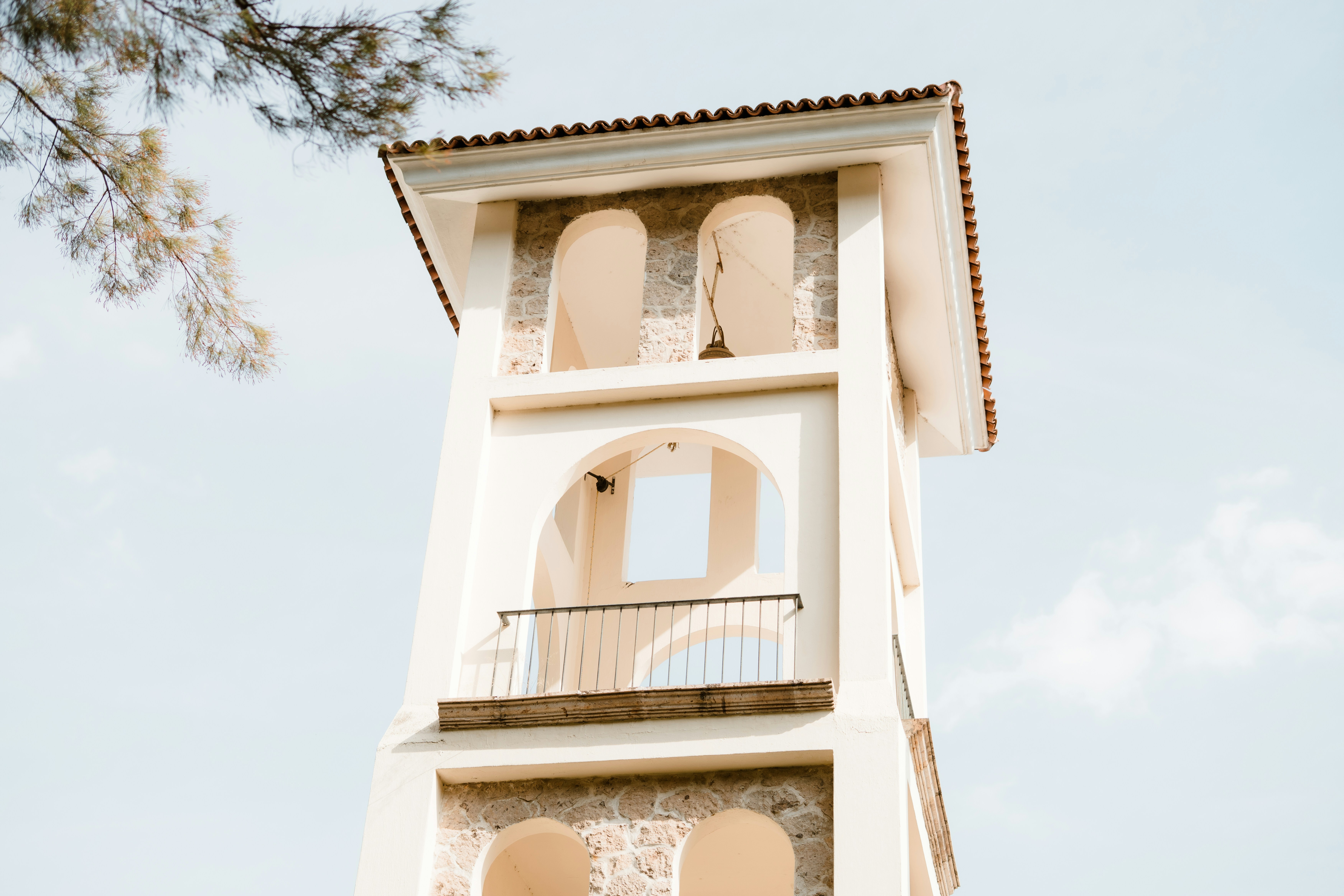 Ein hoher weißer Turm mit Bogenfenstern und einem Balkon.