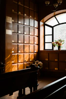 Rows of wooden niches with flowers near a window