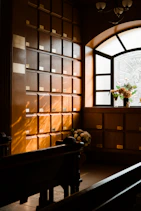 Rows of wooden niches with flowers near a window