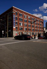 A black convertible car drives past a brick building.